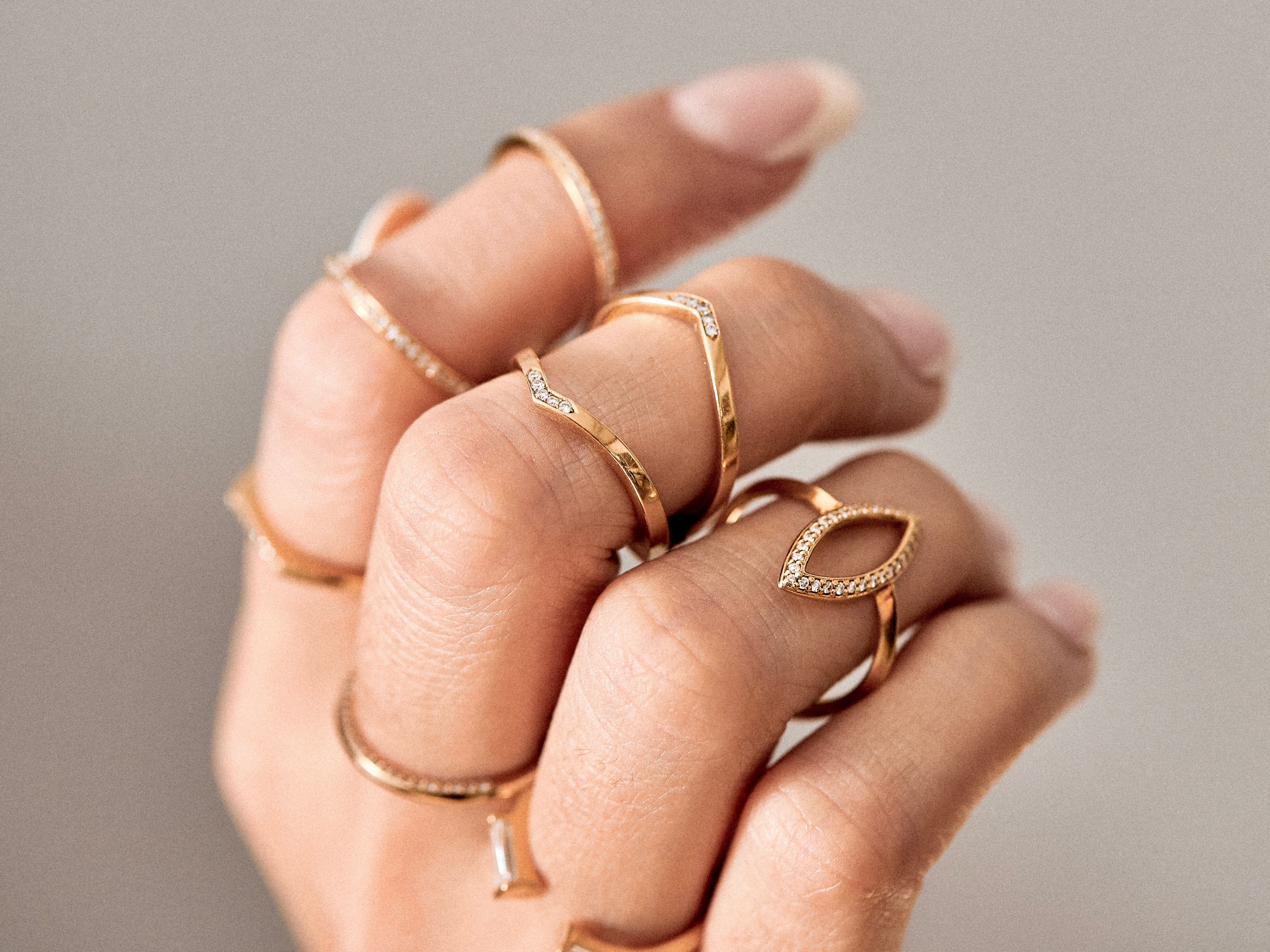 Elegant interlocking wedding bands displayed on green leaves, showcasing intricate designs with sparkling pavé accents in gold. Perfect for symbolizing timeless love and commitment.