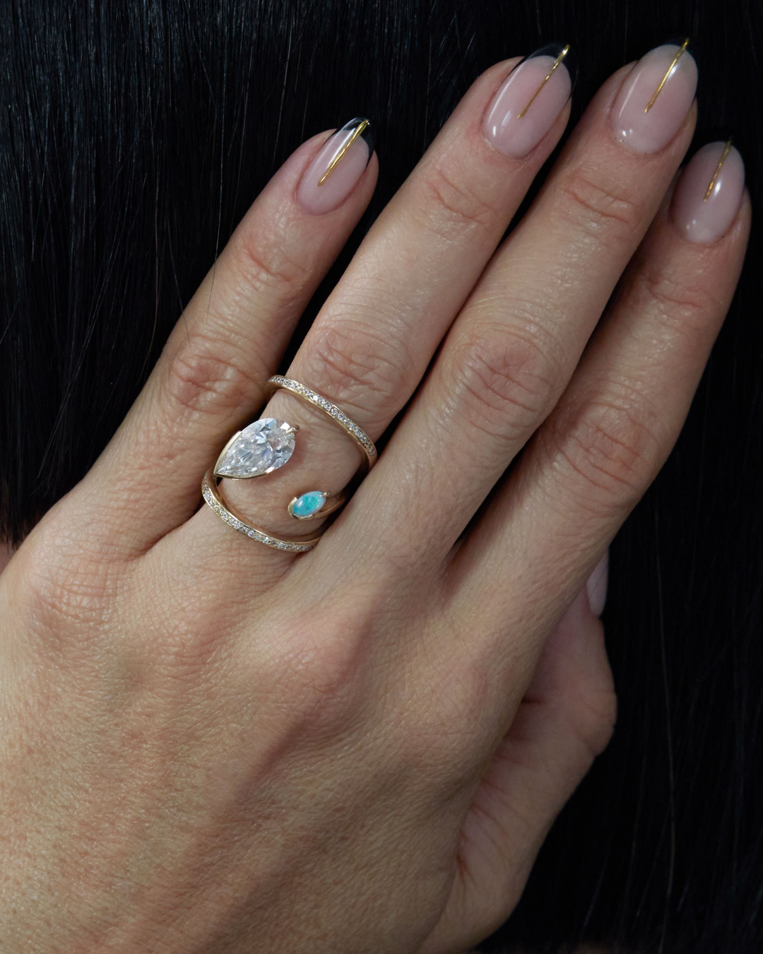 Elegant hand wearing the Intuitive Ring Sun Diamond by Bliss Lau, showcasing a pear-shaped diamond and a vibrant Australian White Opal in a luxurious 14k Fairmined Gold setting.