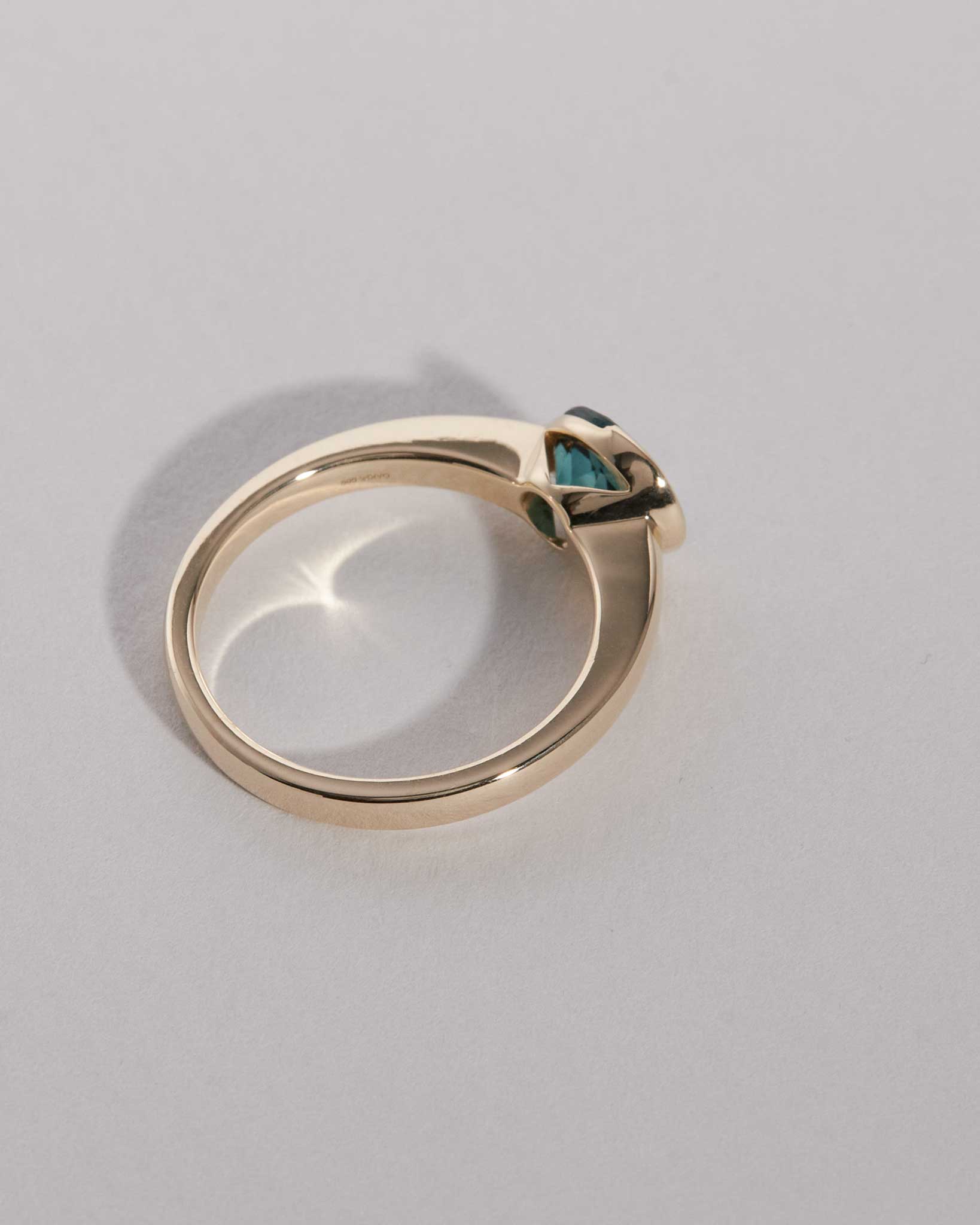Gold ring with a blue gemstone on a gray background