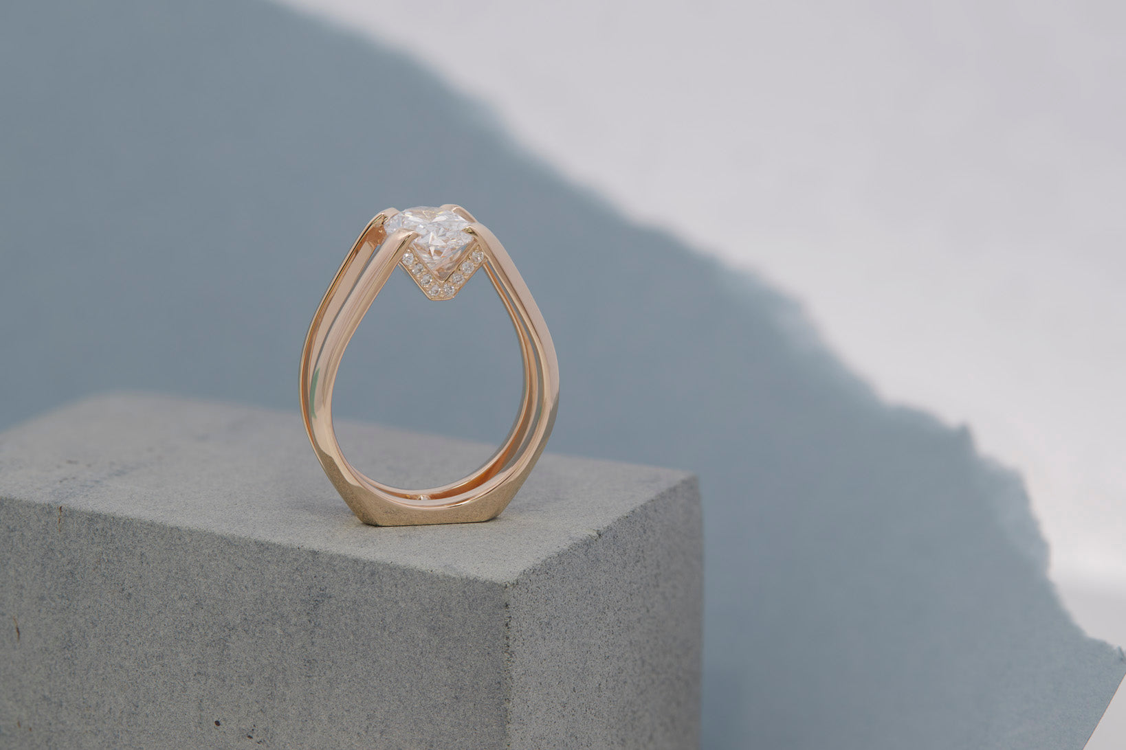 Futurist Engagement Ring Signature Collection featuring a striking heart-shaped diamond set in a unique double band design, showcased on a sleek concrete pedestal.