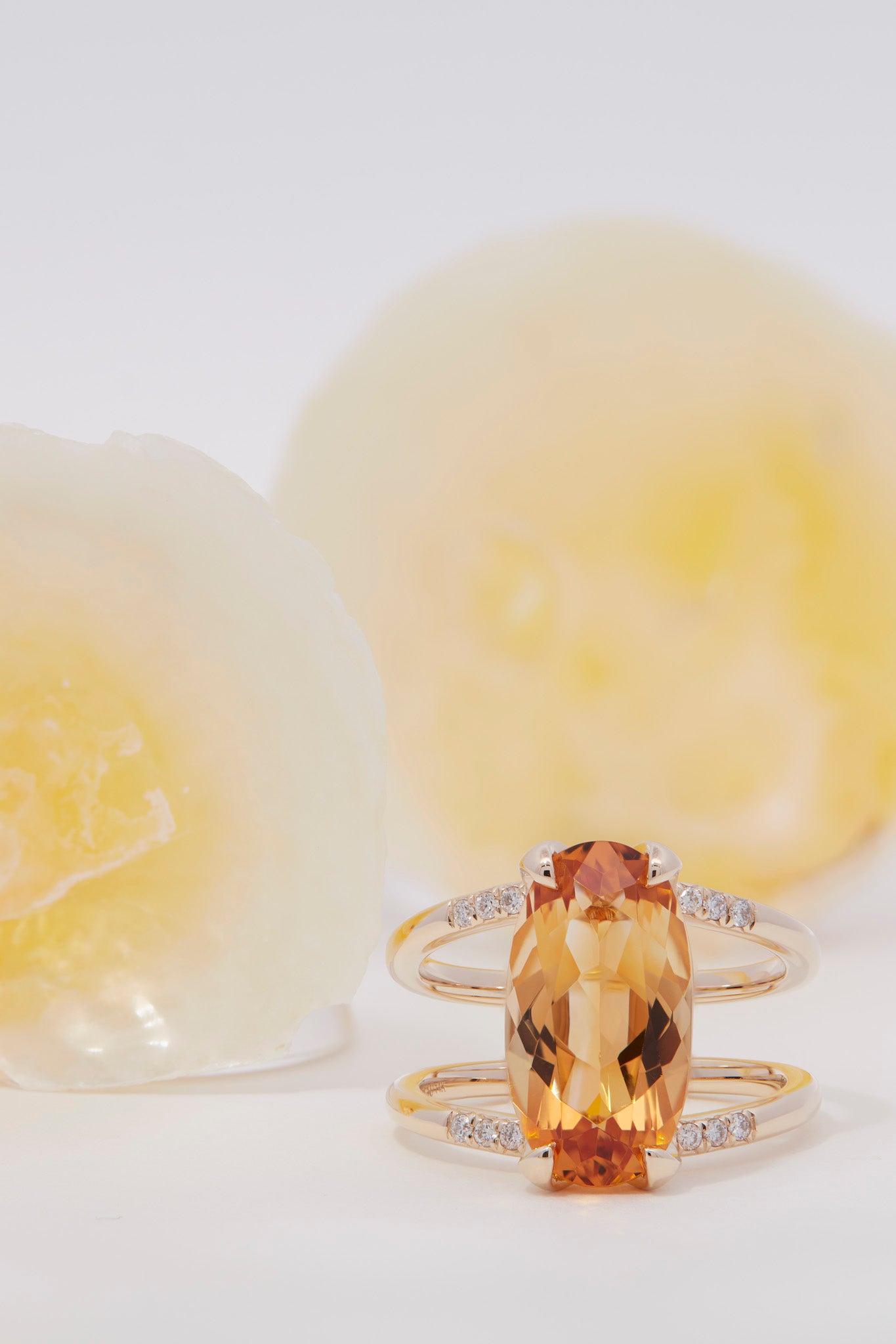 Illuminate Engagement Ring Signature Collection highlighting an exquisite oval orange gemstone surrounded by diamonds, beautifully presented with a delicate, soft-focus backdrop.