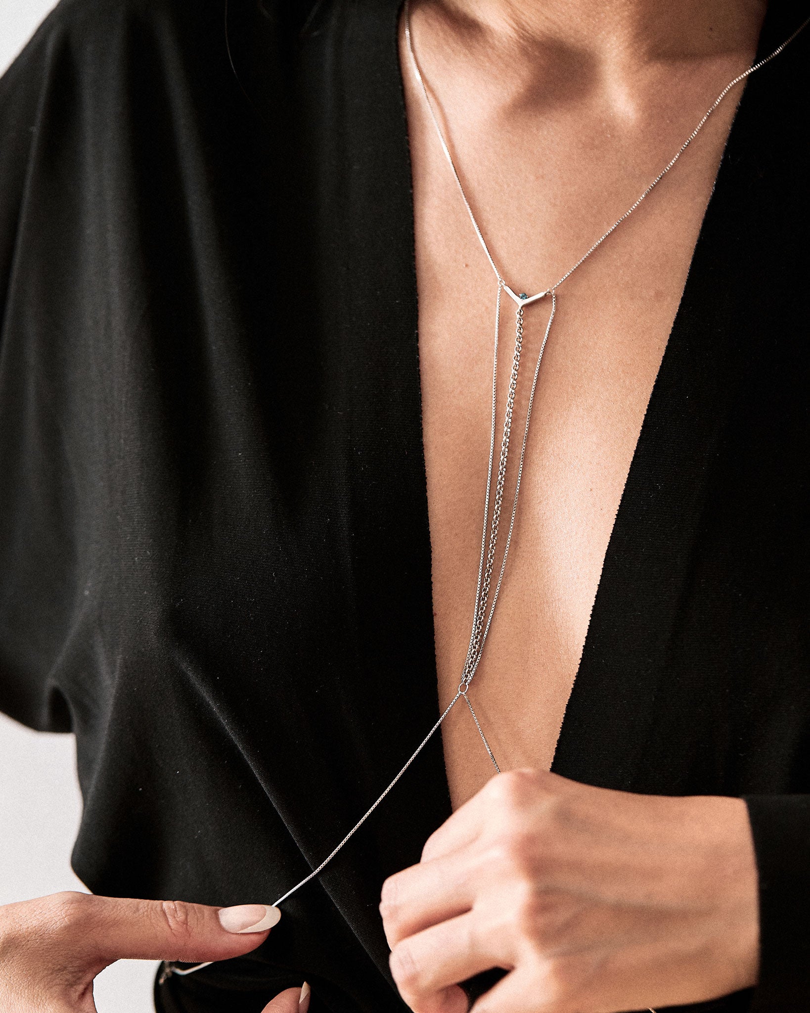 Model showcasing the Interlude Bodychain Aquamarine elegantly draped over a black outfit, emphasizing the sensual design with diamond detail and balanced structure.