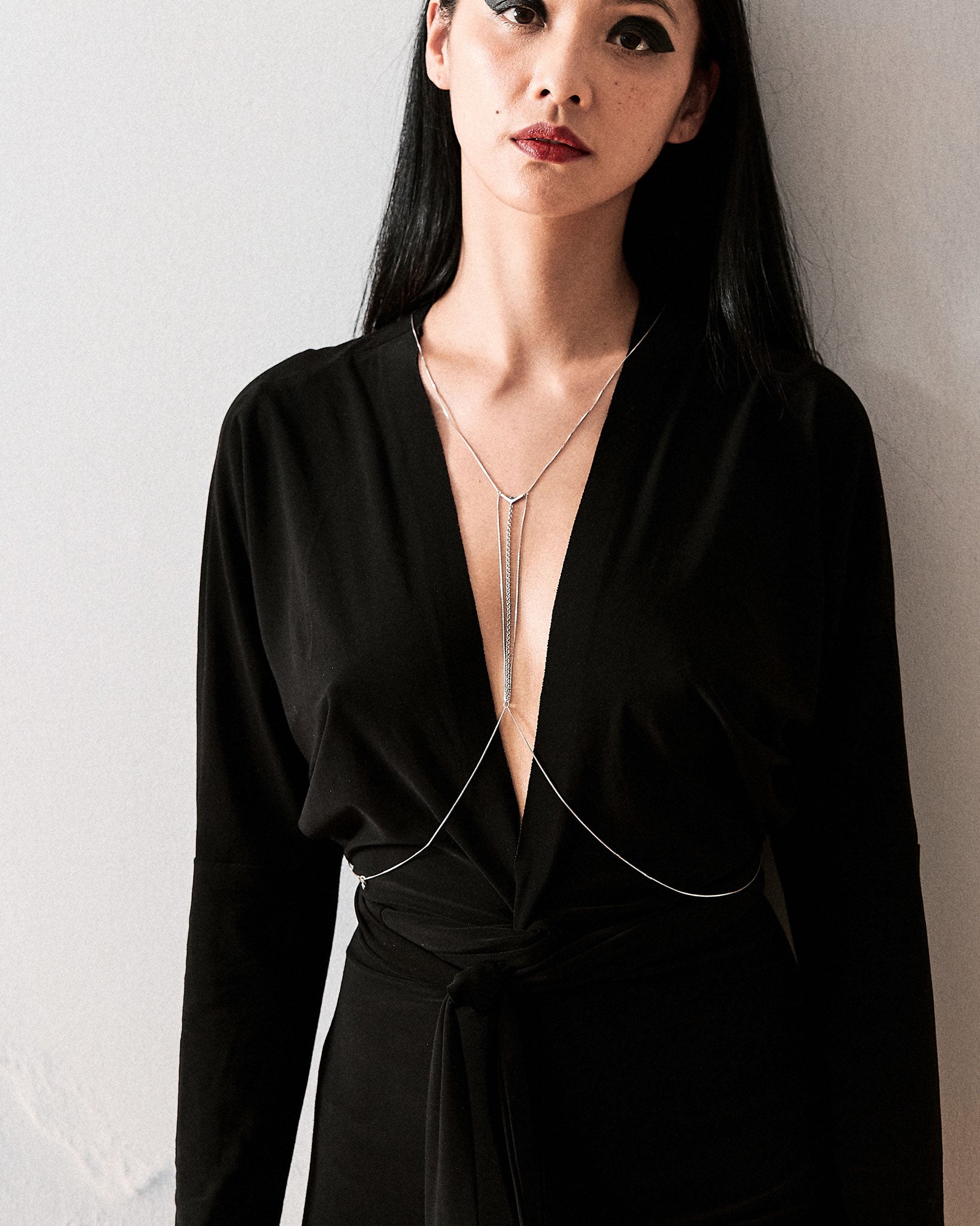 Model wearing the Interlude Bodychain Aquamarine, paired with a sophisticated black ensemble, showcasing the bodychain's alluring design and femininity.