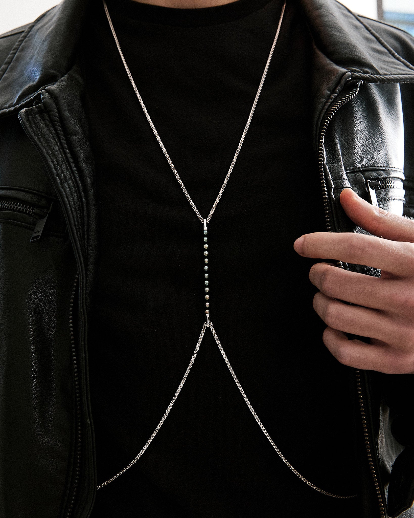 A model showcasing the Limited Edition Tuxedo Black Bodychain with a striking design featuring sterling silver and black pearls. The bodychain elegantly drapes across the chest, accentuating the body's natural curves, adding a luxurious touch to any outfit.
