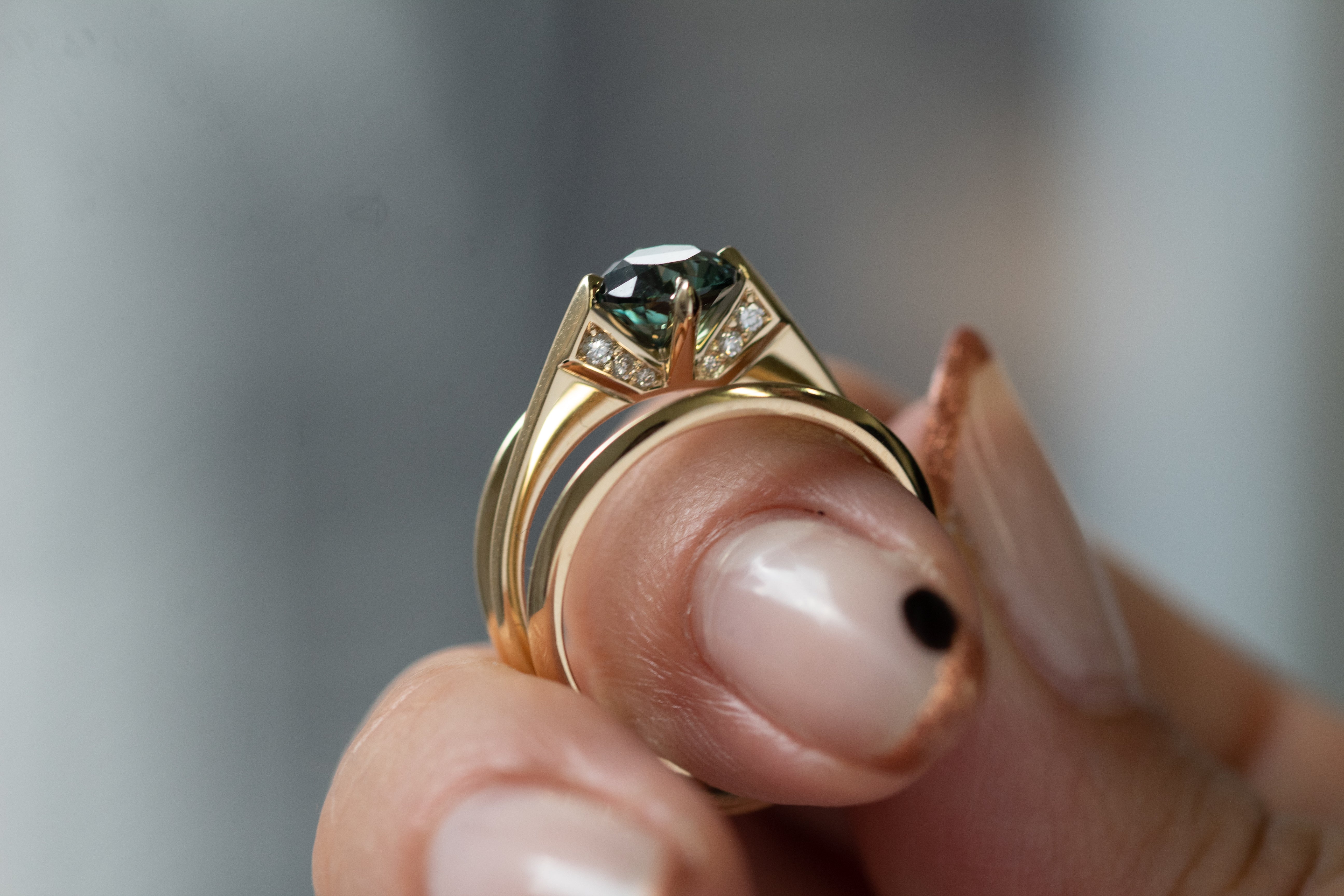 A beautiful minimalist gold ring shines against a dark backdrop, illustrating the features of Bliss Lau's minimalist arc, minimalist rise, and minimalist pave.