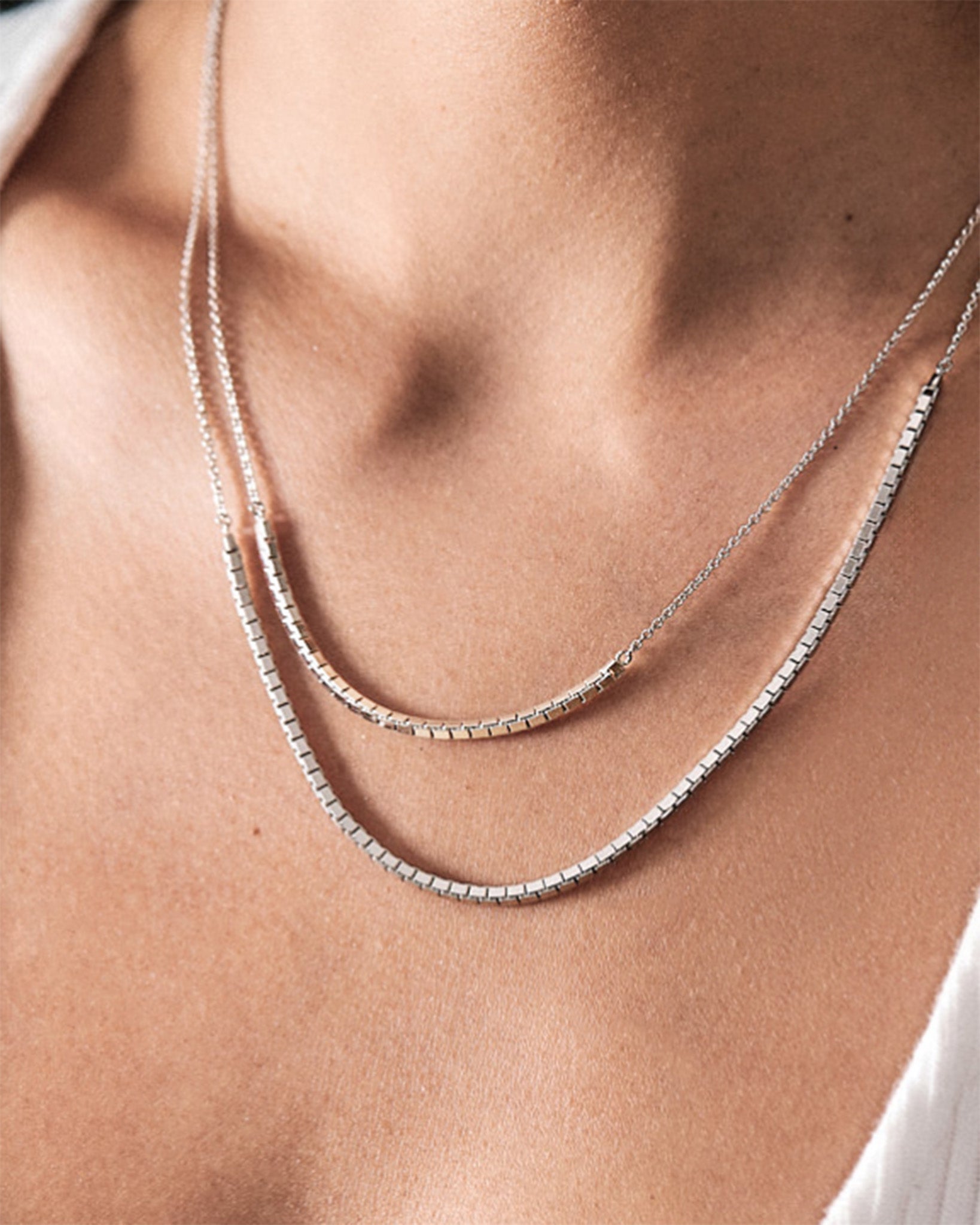 The HALO JOY Max Sterling Silver Necklace elegantly layered around a woman's neck, showcasing its exquisite design and craftsmanship.