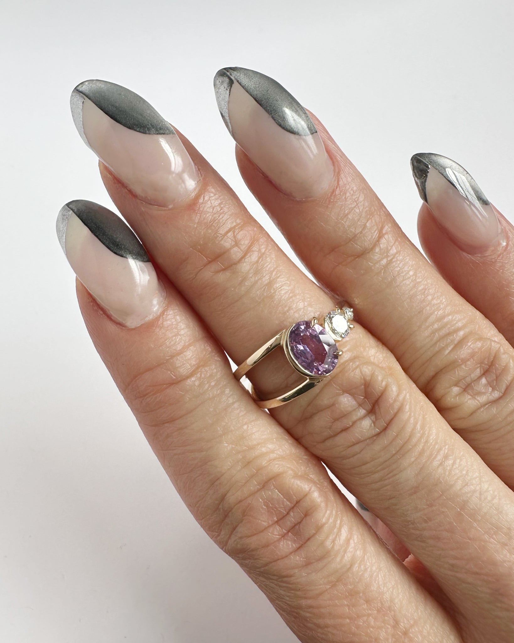 Artistic display of the Bright Ring Lilac Sapphire on a hand with stylish nails, emphasizing the luxury and elegance of the ring's design and gemstone.