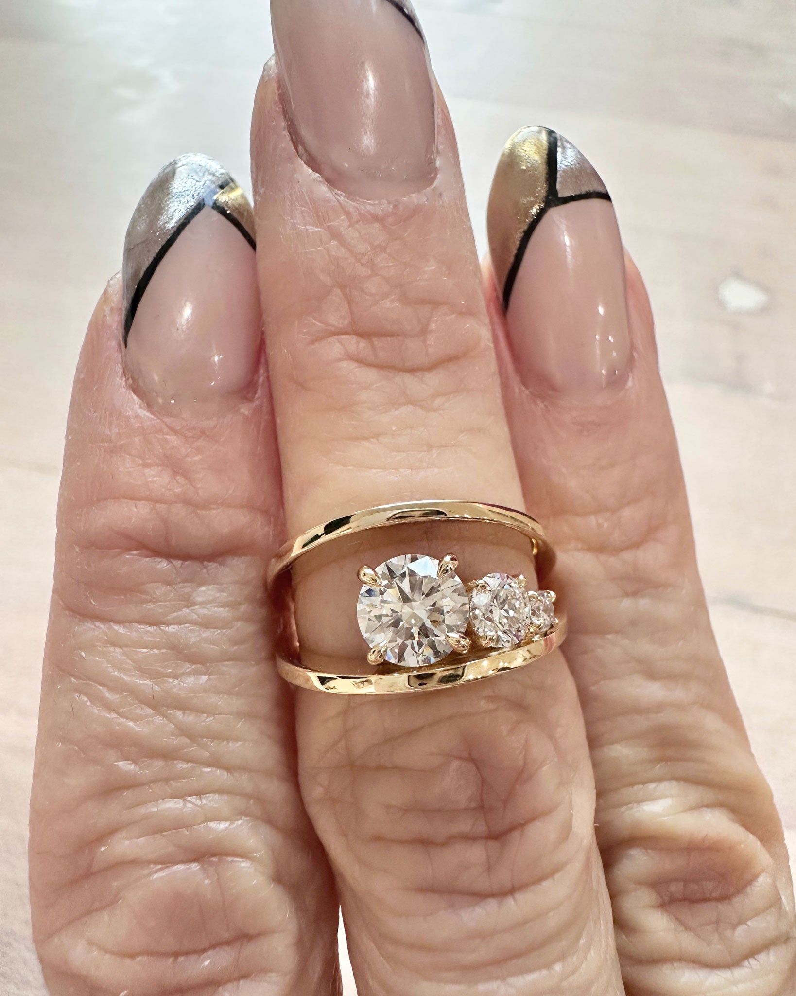 Close-up of the Empath Engagement Ring with two brilliant diamonds and a captivating gold band, highlighting its unique craftsmanship and elegance.
