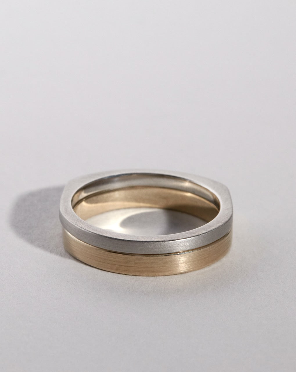 Two wedding bands in gold and platinum finish on a light gray background