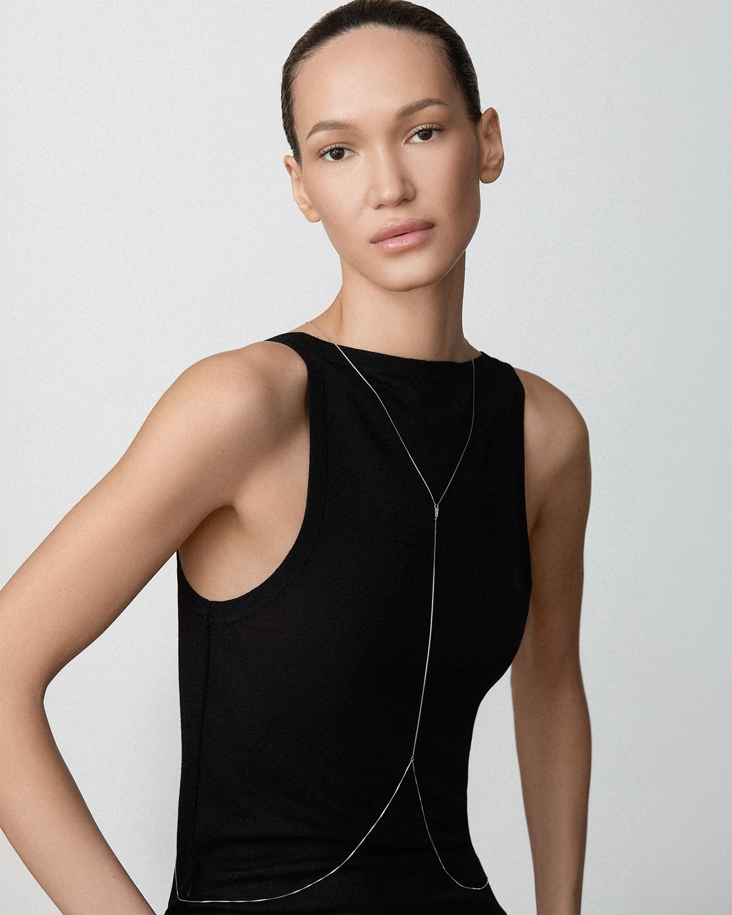 A model wearing a Bliss Lau sterling silver Blink body chain over a black sleeveless top, photographed against a light gray studio background.
