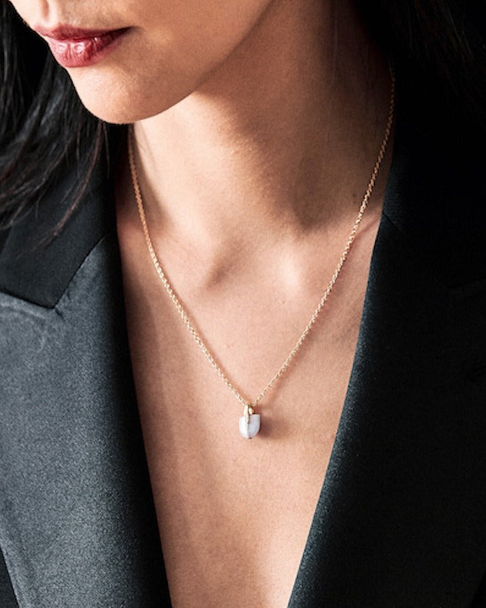 Person wearing a platinum necklace featuring a small lavender jade pendant