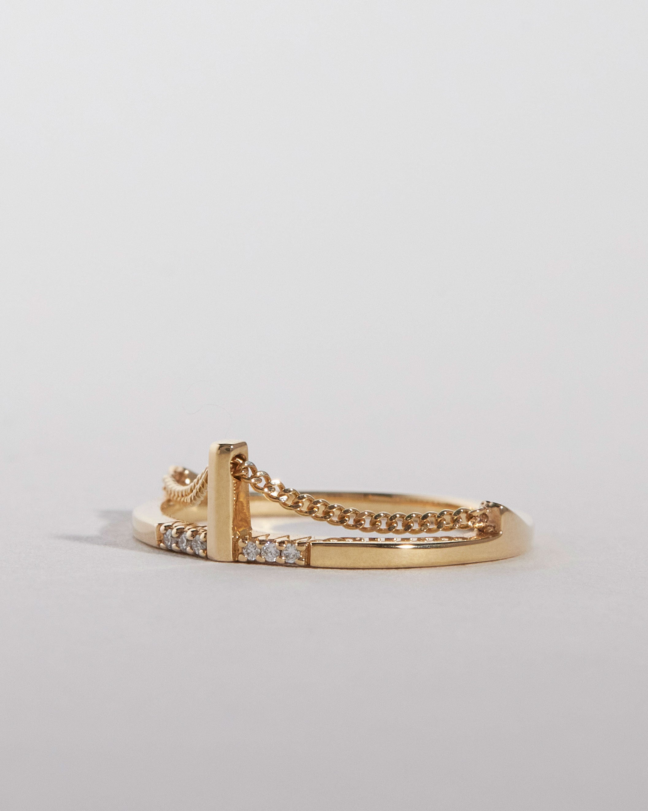 Gold ring inspired by the Brooklyn Bridge with chain design on a light gray background