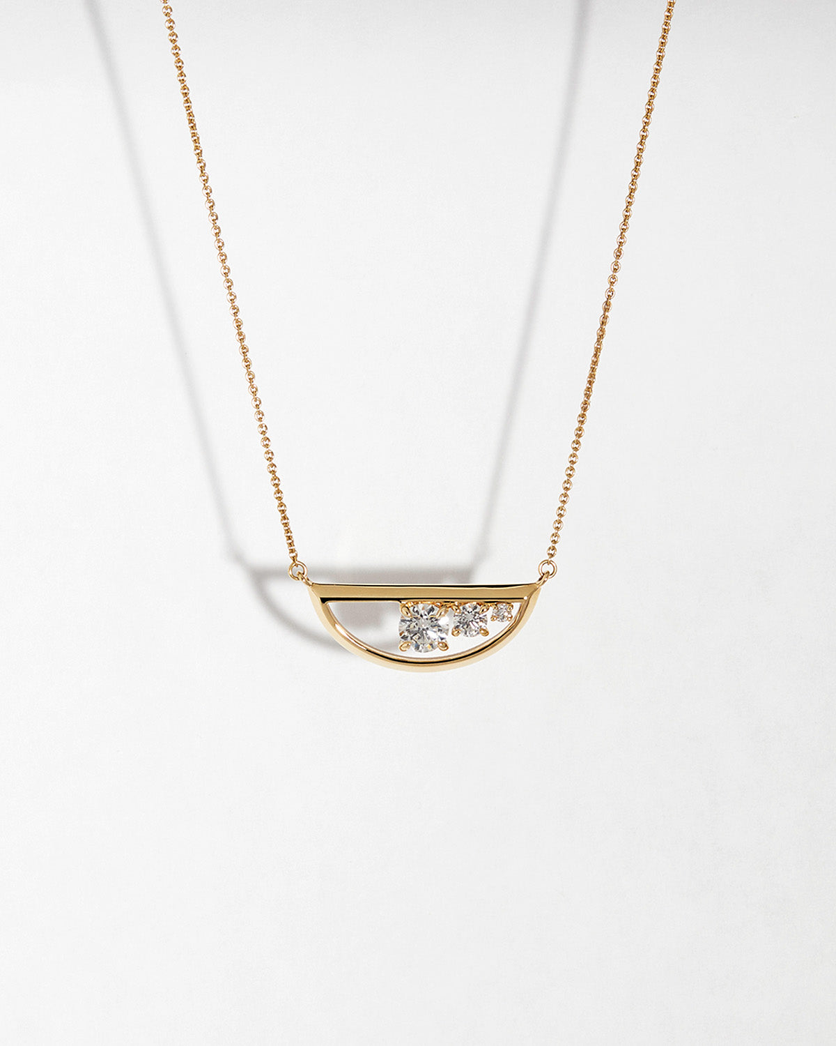 Gold necklace with a half-circle pendant with diamonds on a white background
