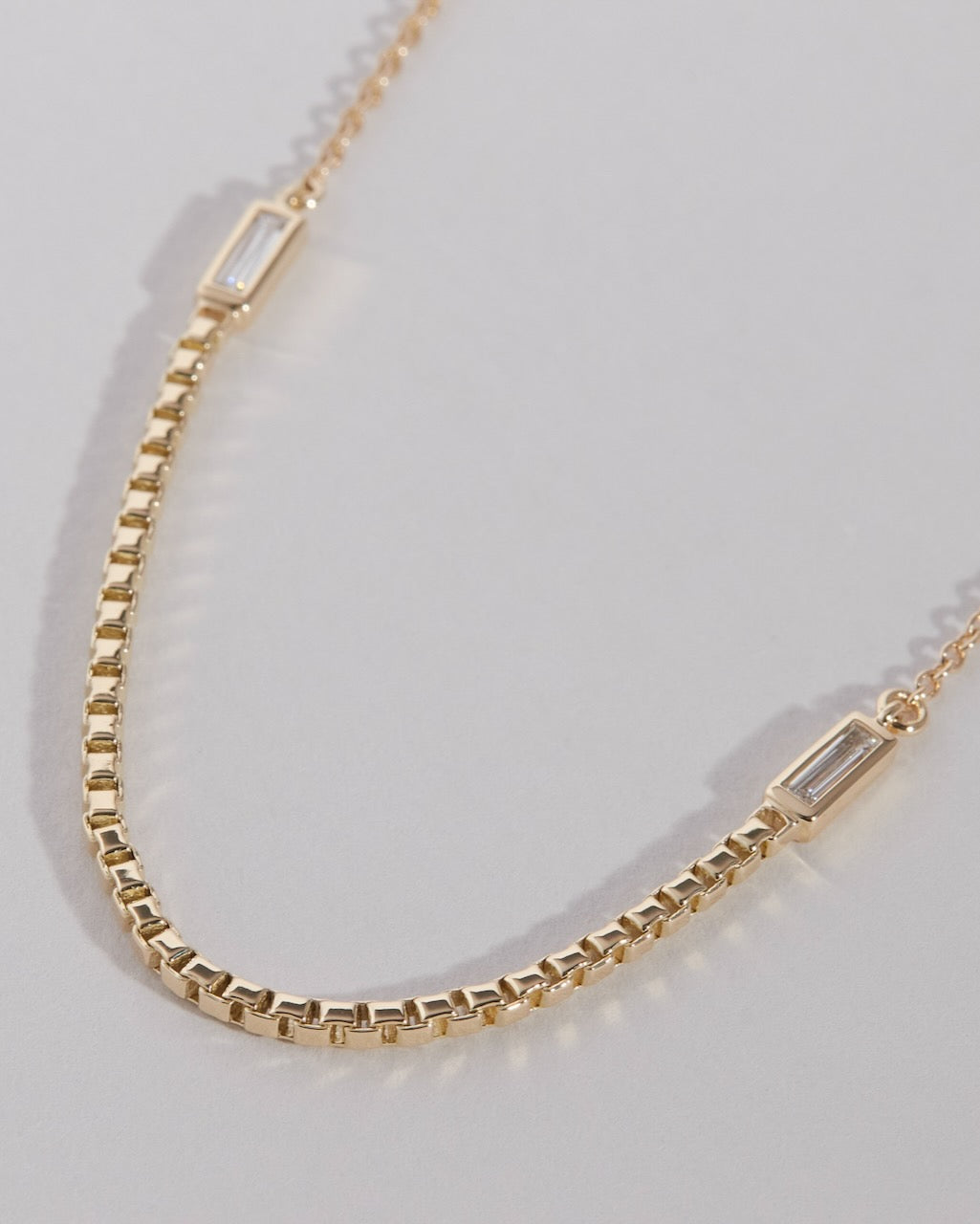Gold necklace with rectangular diamonds on a light gray background