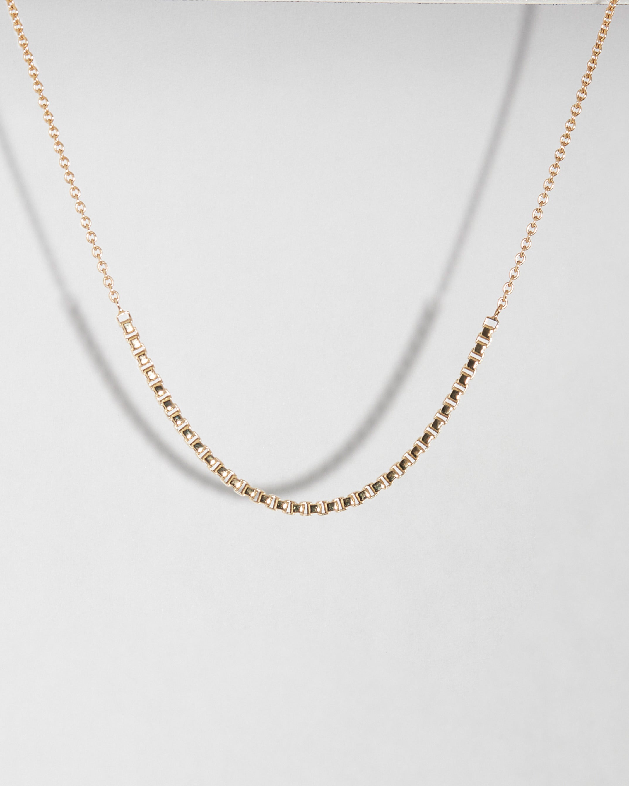 Gold chain necklace on a light gray background
