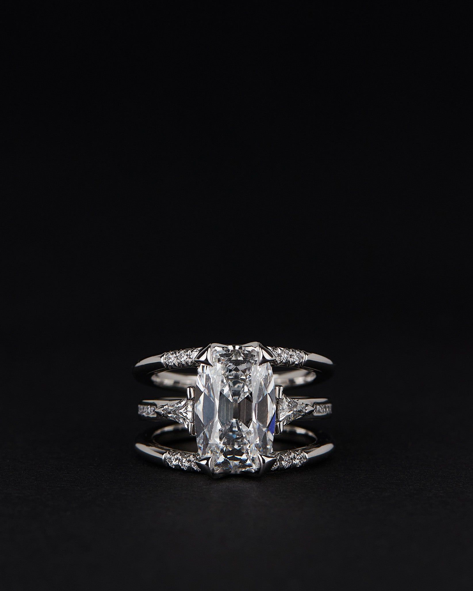Bliss Lau Illuminate Magnetic Interlocking Ring set in platinum with lab grow diamond. The double-band ring set featuring a lab grown diamond and an open band with matching triangular stones in the Magnetic ring, shown on a black background.