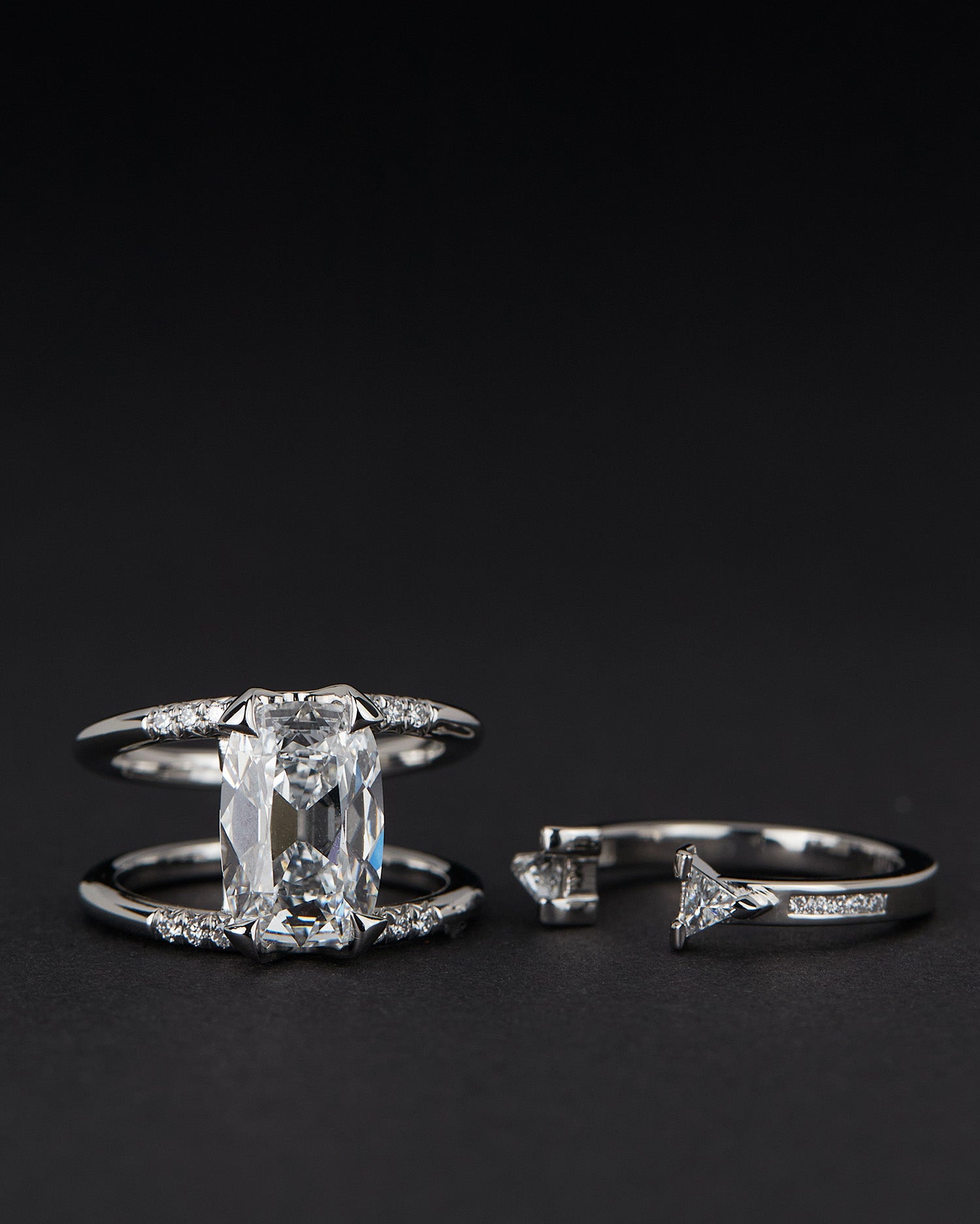 Bliss Lau Illuminate Magnetic Interlocking Ring set in platinum with lab grow diamond. The double-band ring set featuring a lab grown diamond and an open band with matching triangular stones in the Magnetic ring, shown on a black background.