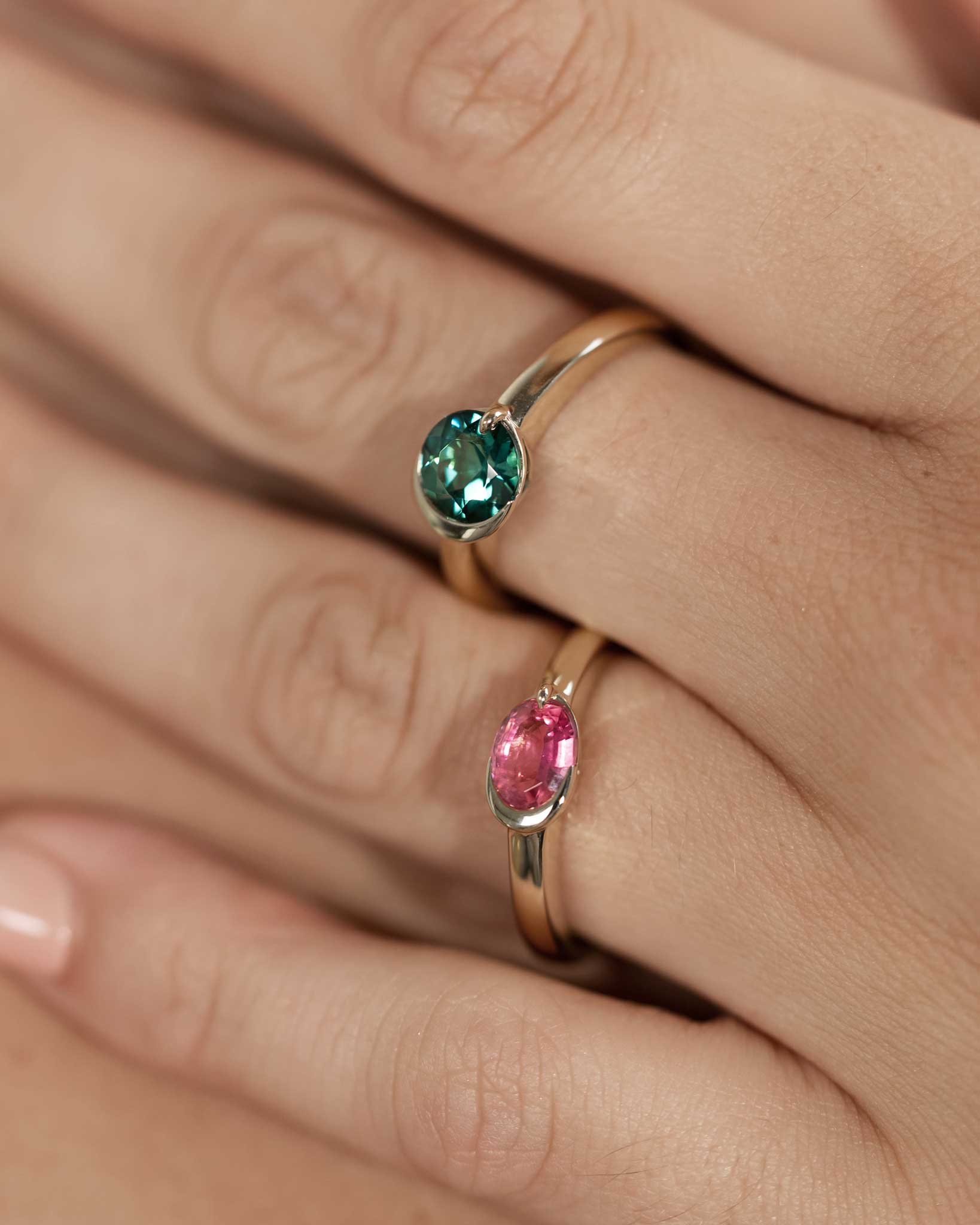 Close-up of two rings with gemstones on a hand