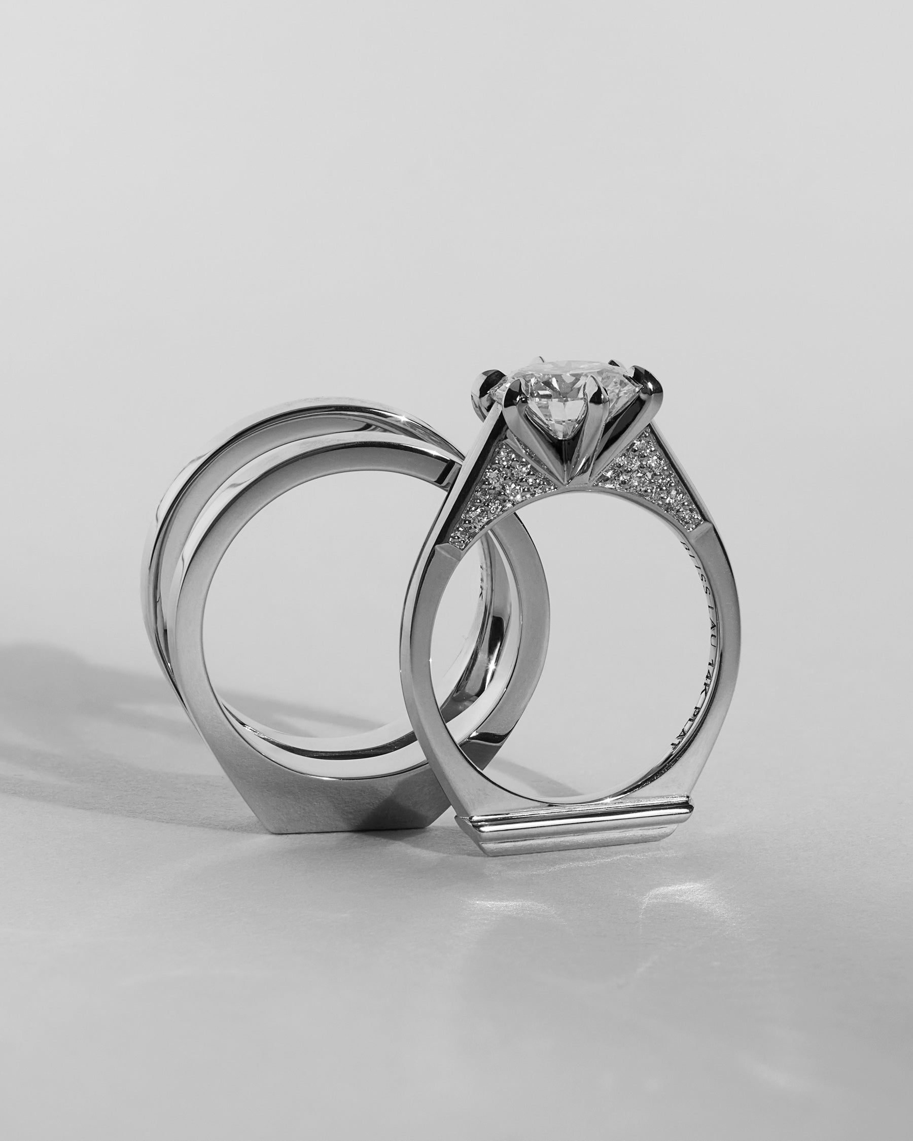 Two gold rings with diamond accents on a light gray background