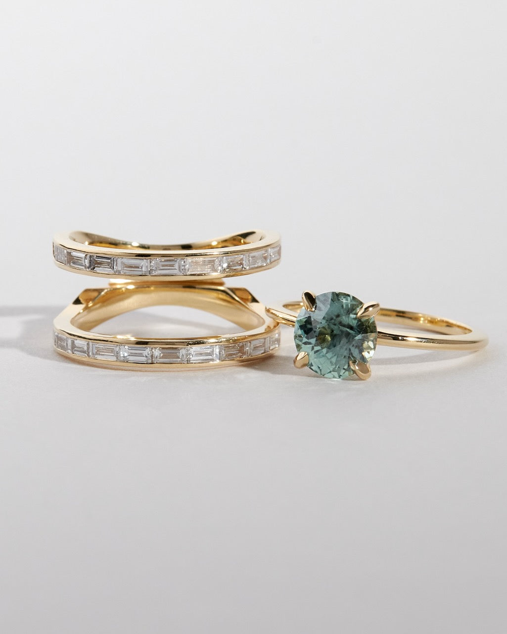 Two gold rings with gemstones on a light gray background