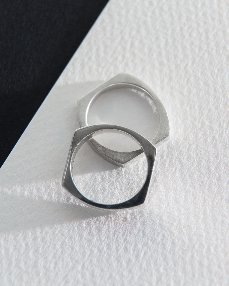 Stylish display of two sophisticated Rational V Bands in a minimalist setting on textured paper, emphasizing their refined design.