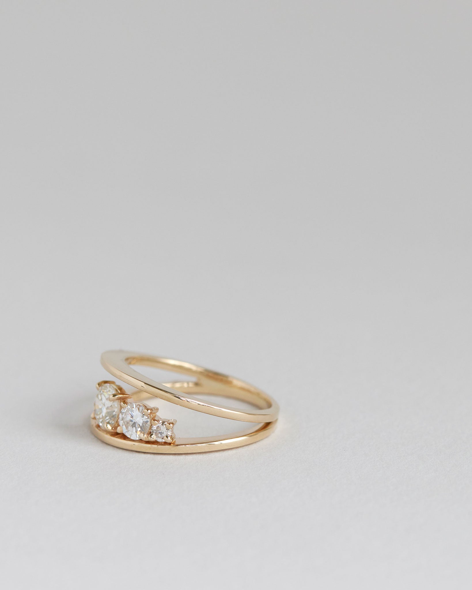 Stylish side view of the Empath Ring against a minimalistic gray background, showcasing the brilliant diamonds and unique design.