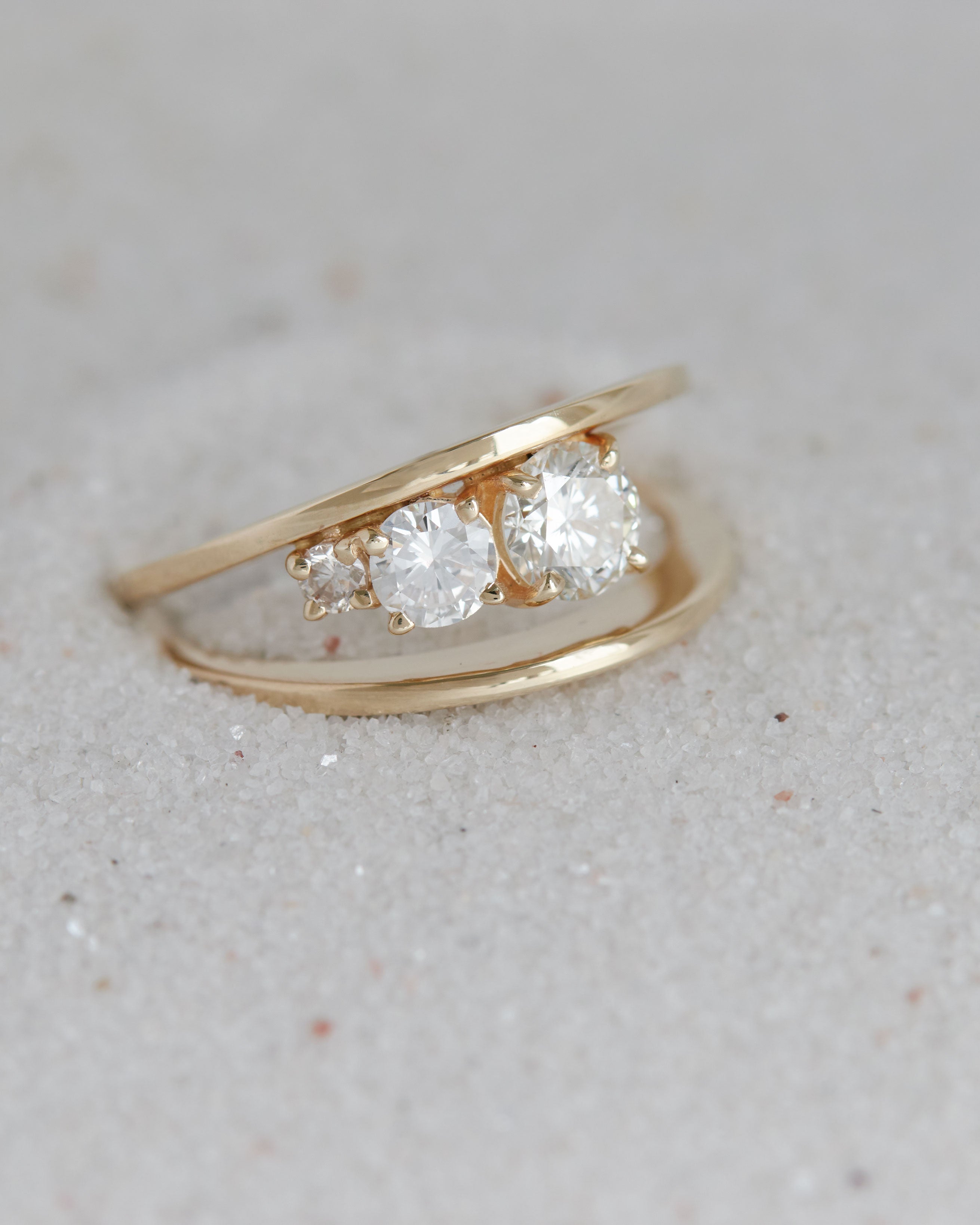 Detailed image of the Empath Ring with diamonds set on a sandy surface, emphasizing its elegance and craftsmanship.