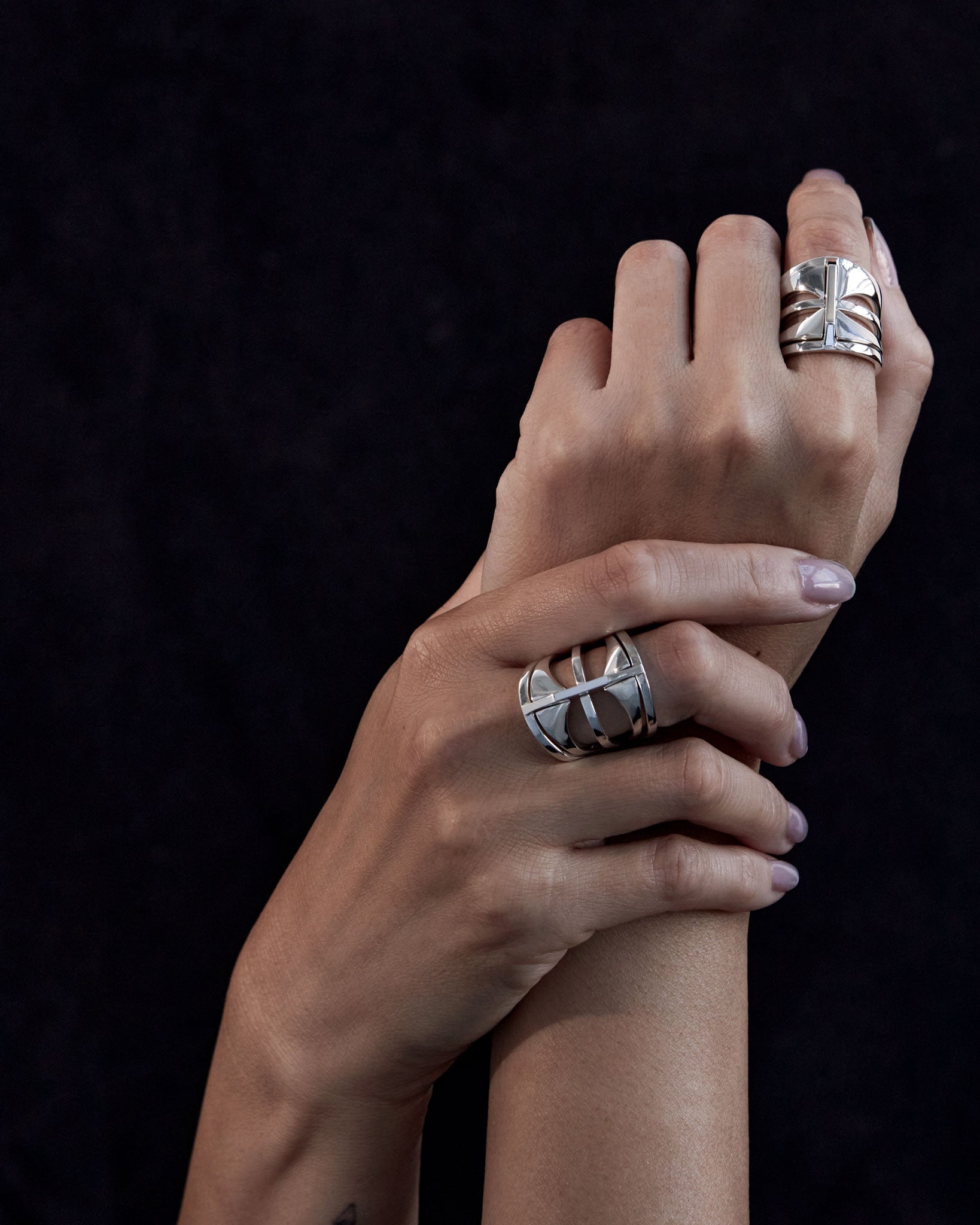 Close-up of a hand displaying the Kaleidoscope ring set, emphasizing its unique shapes and clean lines in gleaming silver.