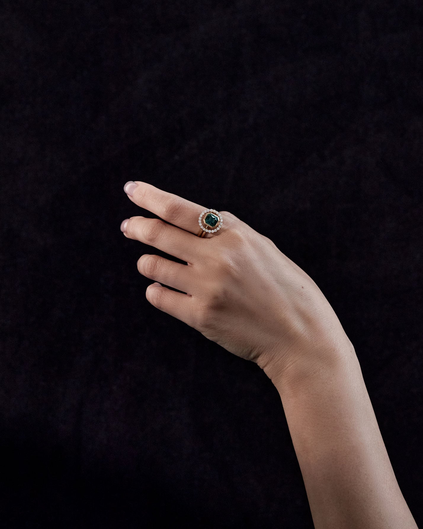 Royale Halo Ring Set worn on a hand, highlighting the elegant design of a green gemstone surrounded by diamonds, perfect for engagements or special occasions.