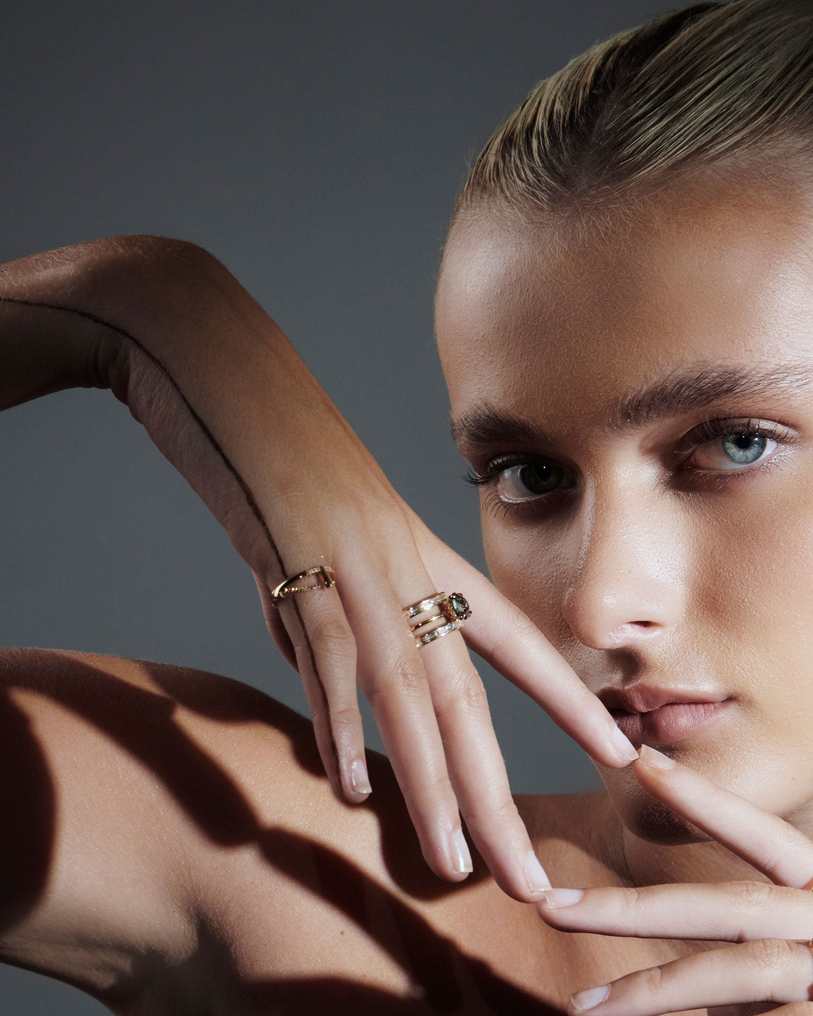 Close-up of a model's hands adorned with Cascade II Enclose Ring, emphasizing its refined diamond baguette setting and modern aesthetic against a striking backdrop.