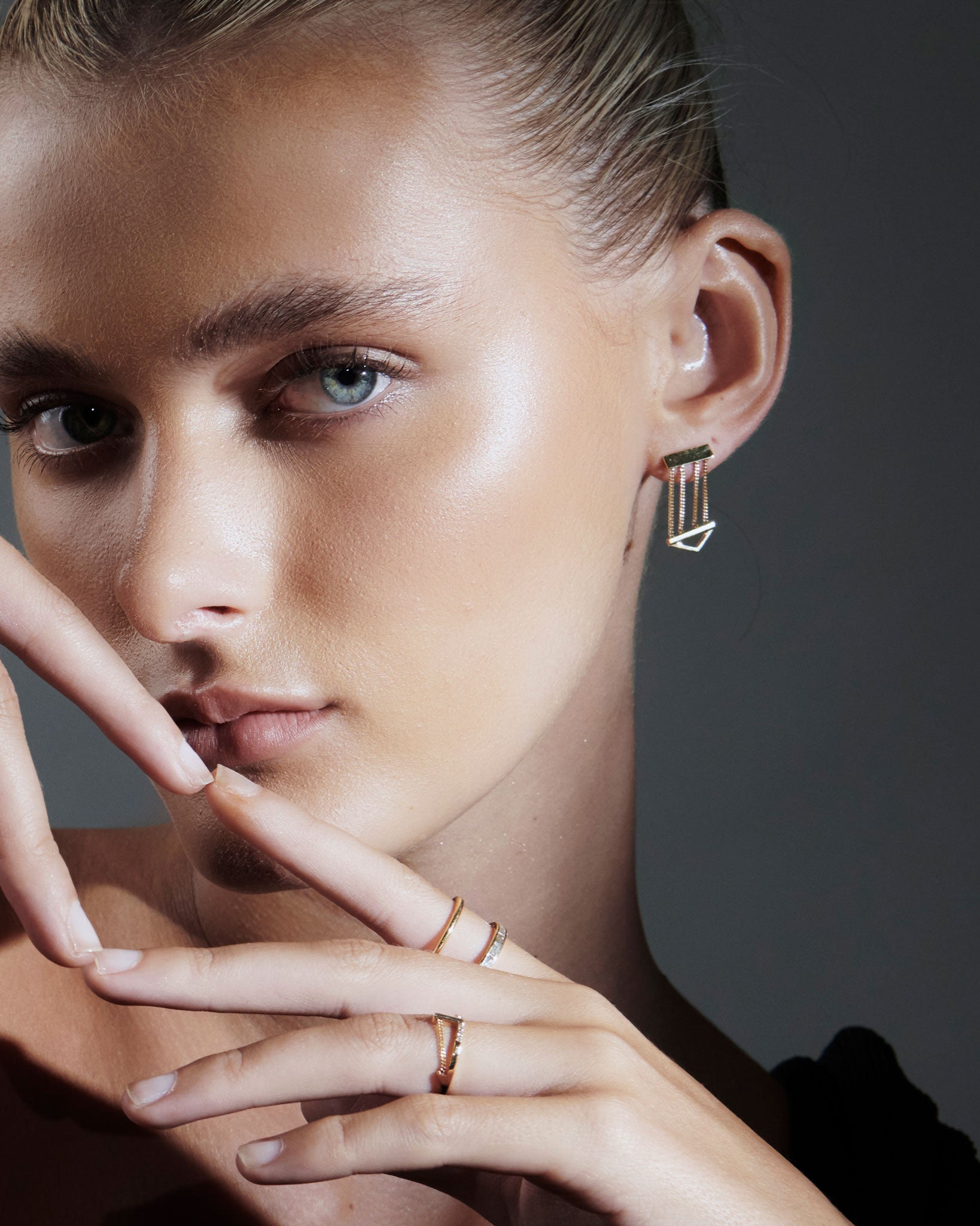 Close-up image of a model showcasing the Cascade Enclose Ring by Bliss Lau, featuring asymmetrical double gold bands and a unique interlocking design. The model's elegant pose highlights the ring’s artistic inspiration and luxury appeal.
