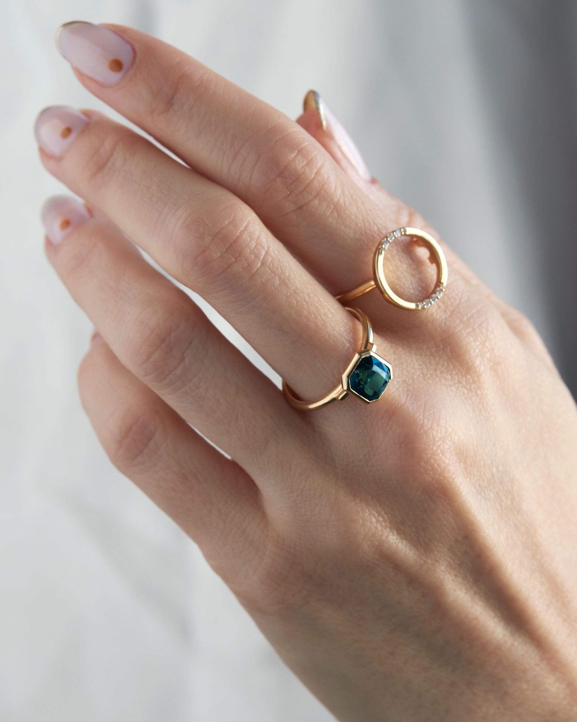 The Royale Ring Set on a hand, featuring an elegant green gemstone ring paired with a minimalist diamond pave band, captured in a pristine white setting.