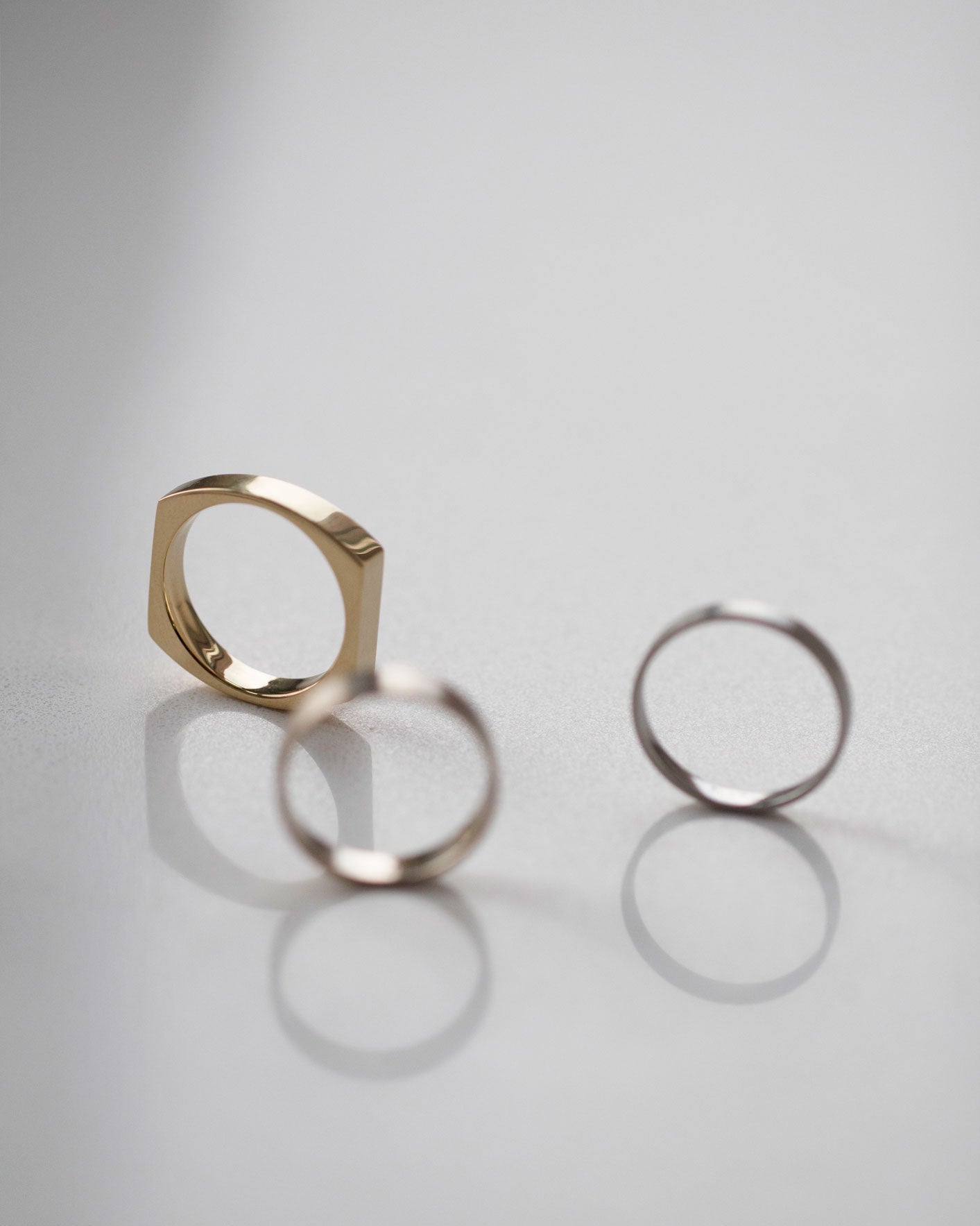 Elegant arrangement of the luxurious Rational V Band in gold alongside sleek silver bands, reflecting versatility in modern jewelry design.