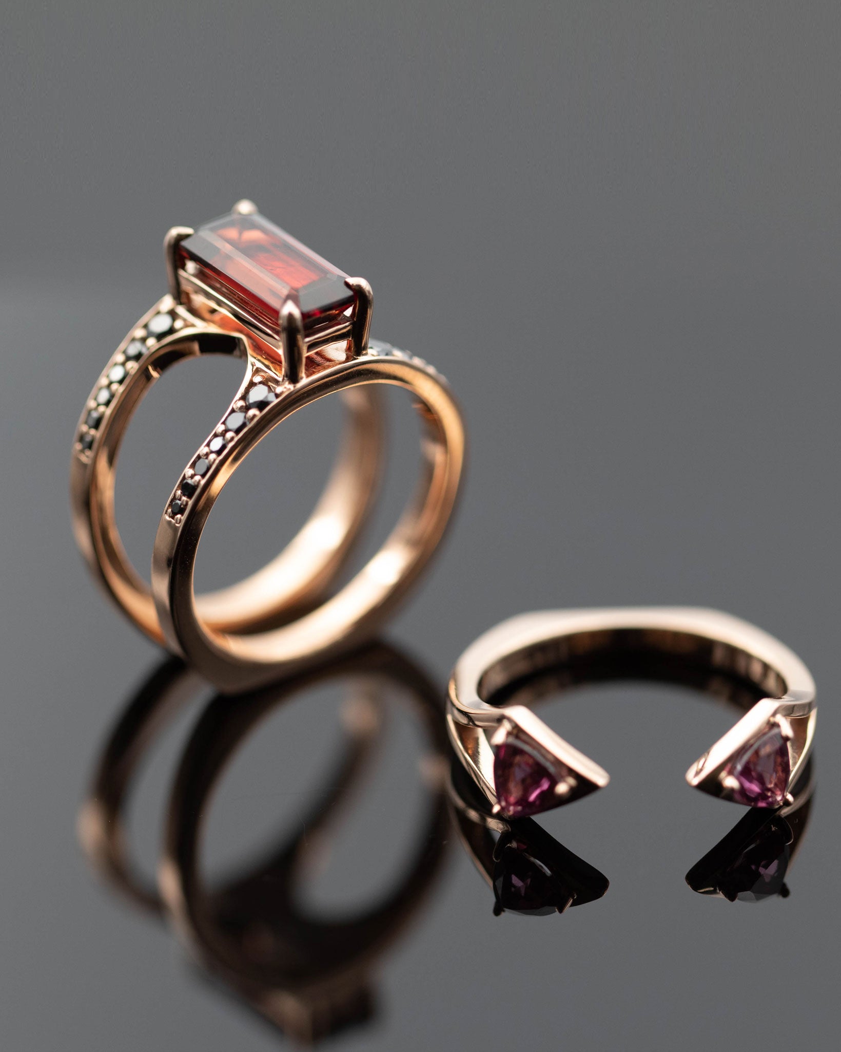 Sophisticated Mirage Ring set featuring a rich dark garnet centerpiece in rose gold, accompanied by complementary ring designs.
