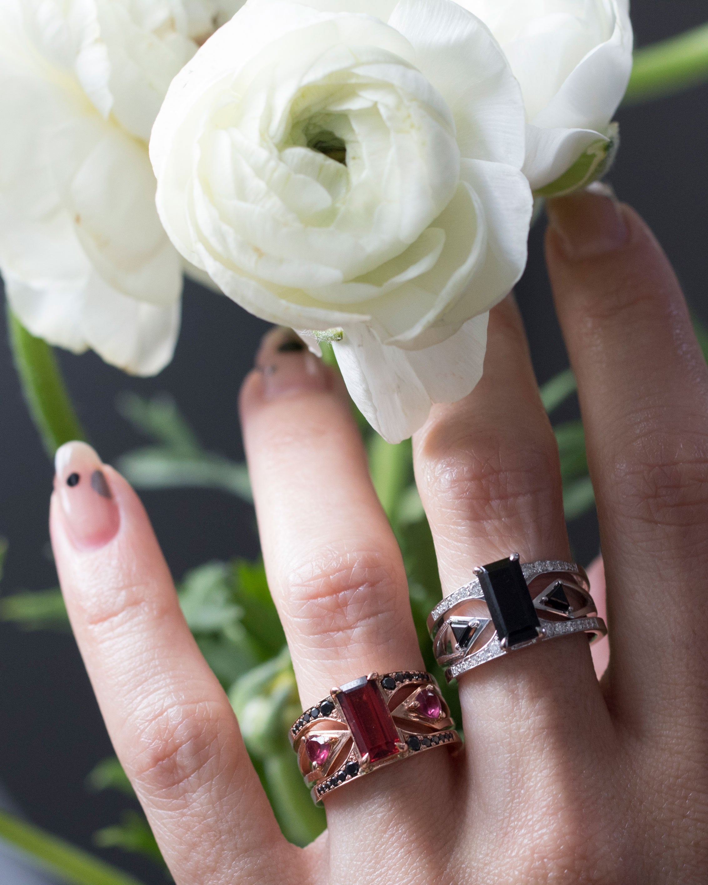 Close-up of the Mirage + Reflection Ring Set, featuring rich black spinel and intricate detailing, beautifully presented with soft floral accents.