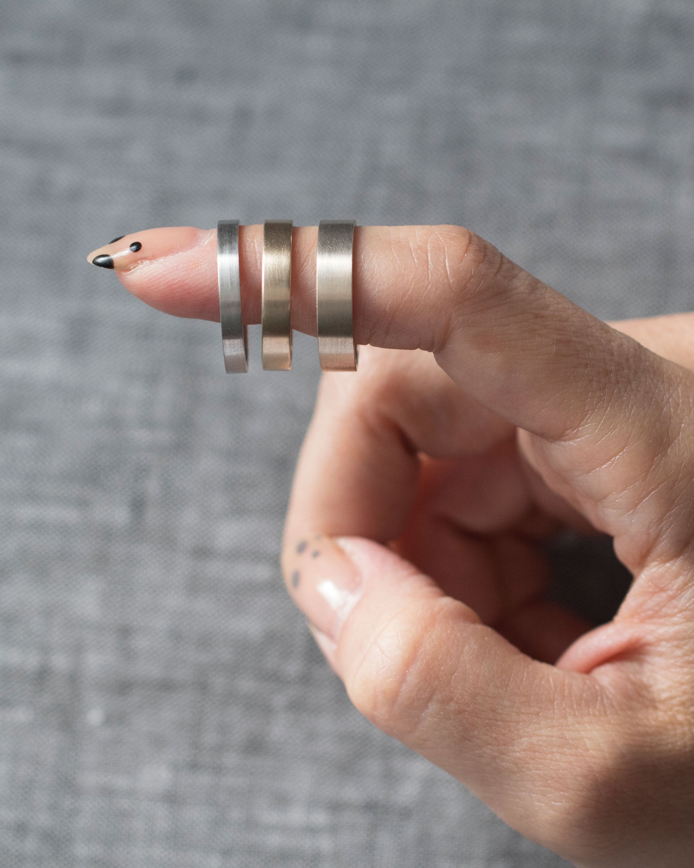 Stylish display of the Trusted III Band by Bliss Lau on a finger, showcasing three different metal finishes for a luxurious look.