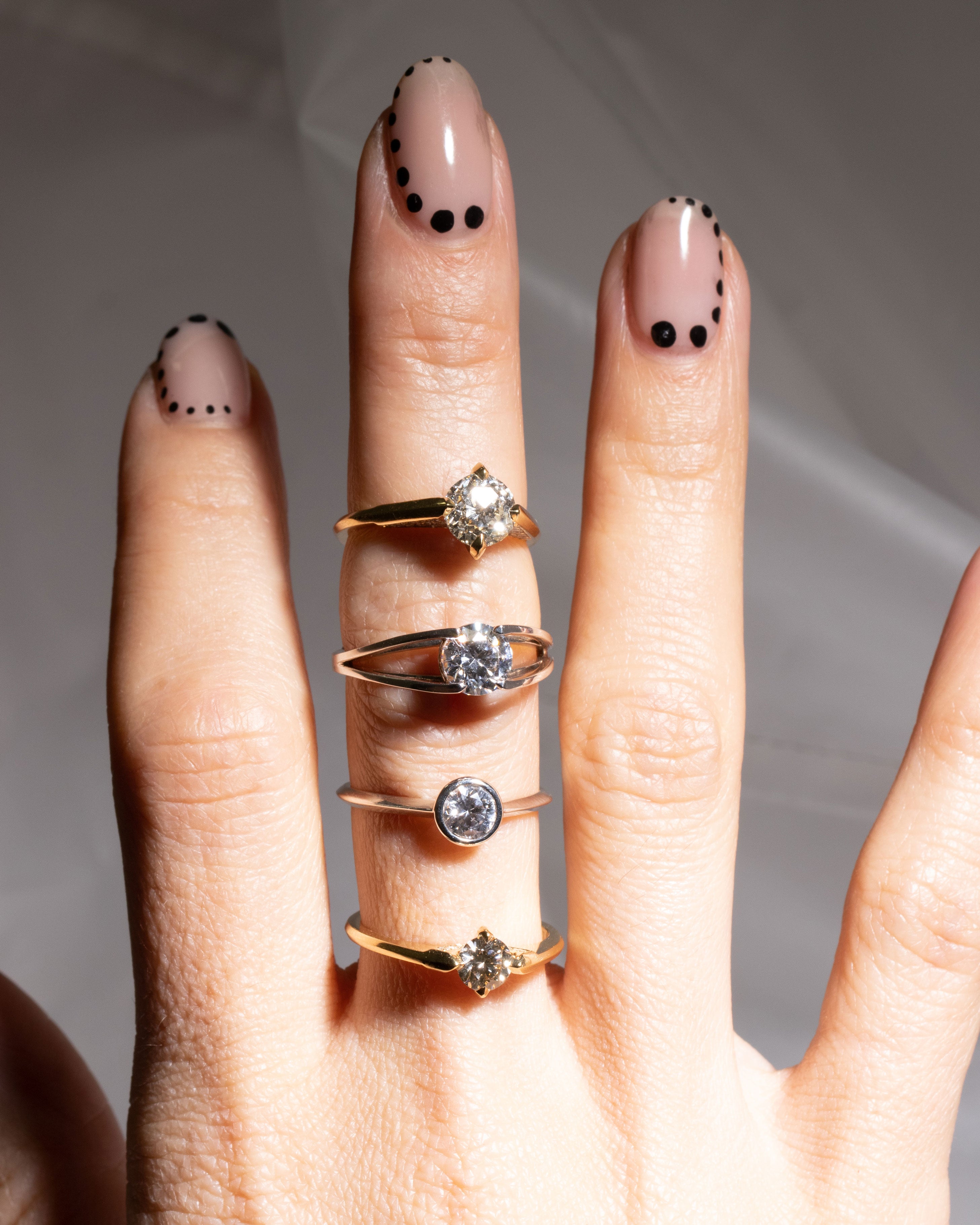 Beautiful hand adorned with multiple Acoustic Engagement Rings, demonstrating the versatility and elegance of Bliss Lau's fine jewelry collection.