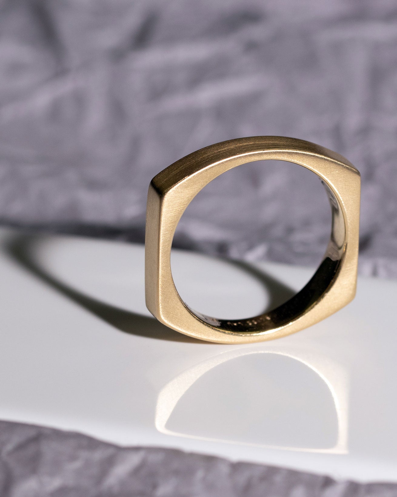 Artistic view of the Rational V Band by Bliss Lau, showcasing its exquisite matte and polished surfaces with dramatic shadow play on a textured background.