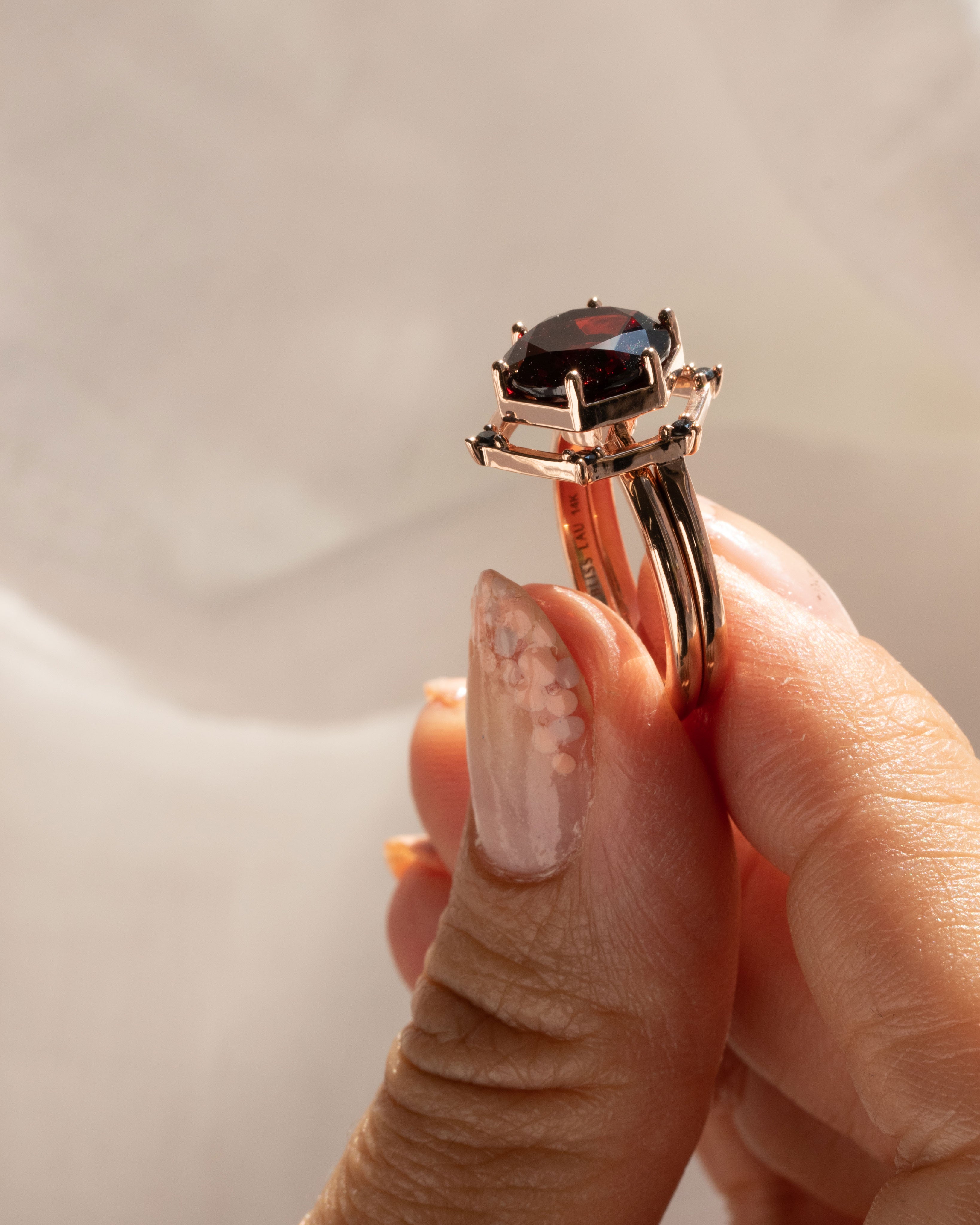 Close-up of the Aura Ring Wedding Ring Set, focusing on the intricate craftsmanship of the octagonal ring holding a radiant round red garnet.