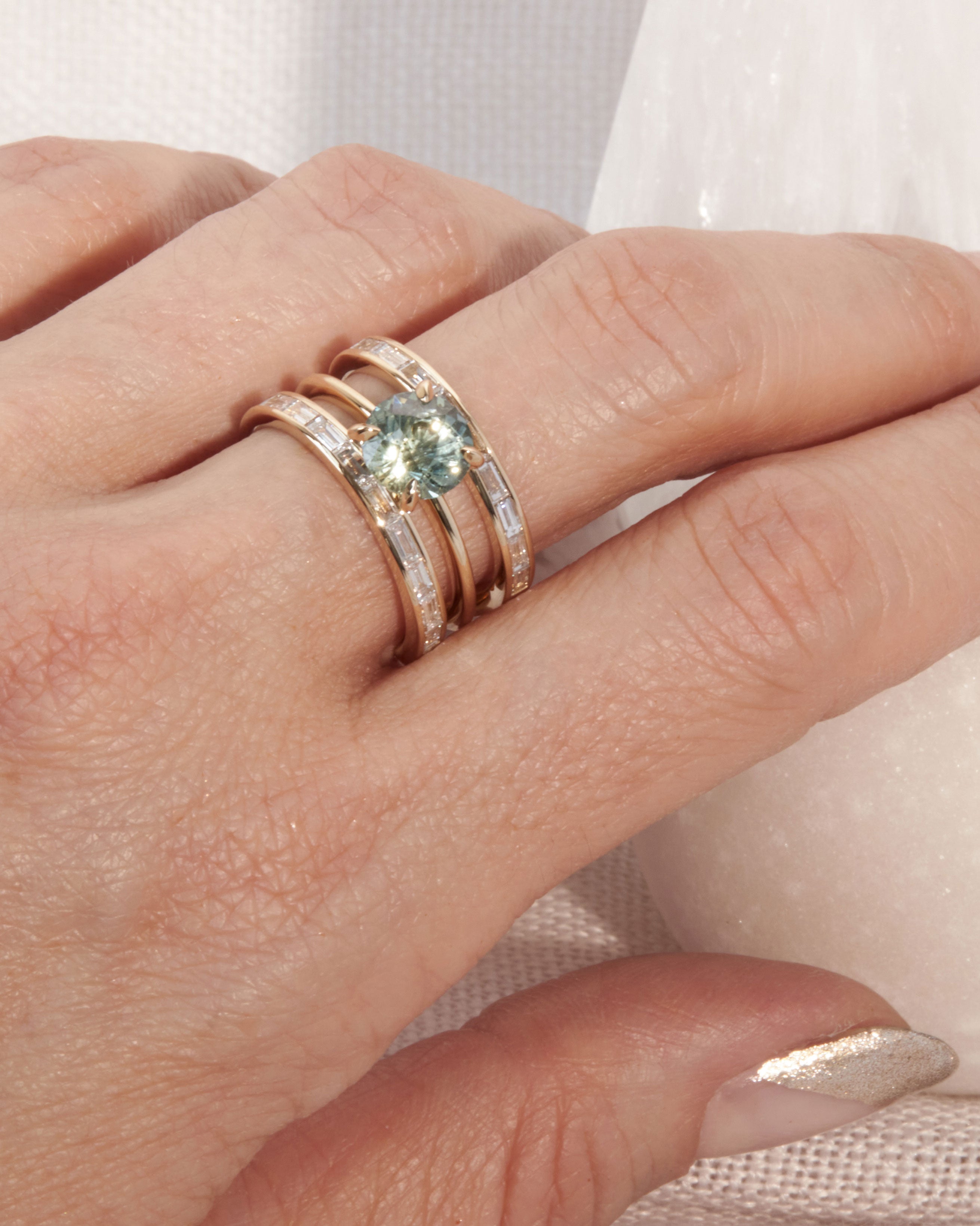 Bliss Lau Poetic Engagement Ring with wedding band interlocking rings on hand.