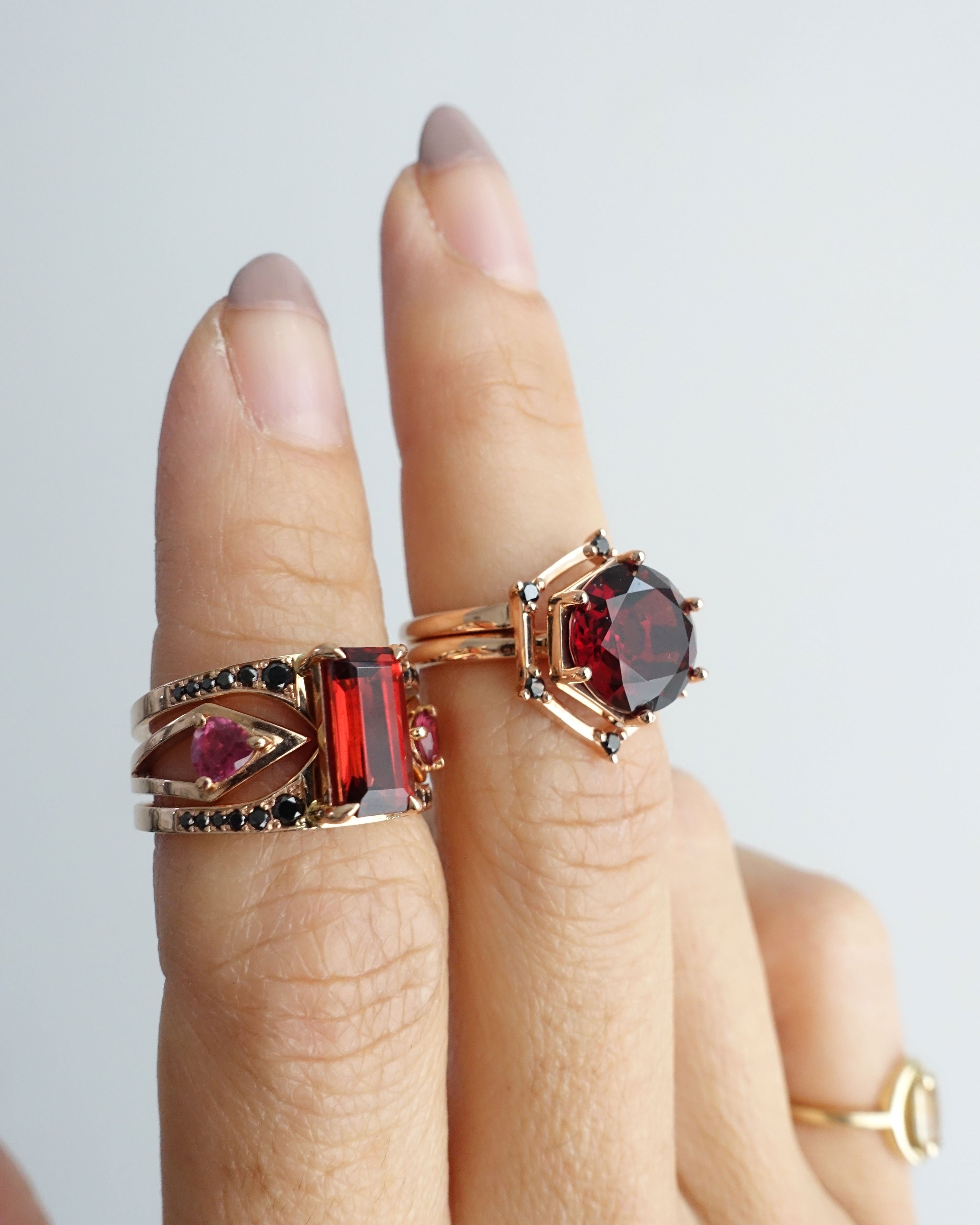Aura Ring Wedding Ring Set featuring an exquisite two-piece design with interlocking rings, showcasing a vibrant 4.85CT round red garnet surrounded by black diamonds.