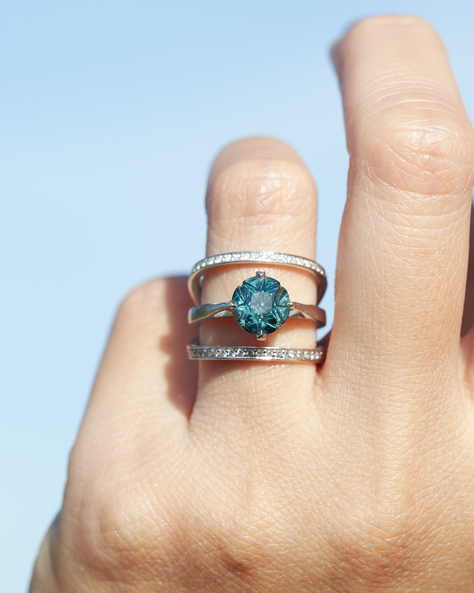 Acute 13mm Enclose Wedding Band showcased on a hand, beautifully complementing a vibrant blue sapphire engagement ring, epitomizing luxury in bridal jewelry.