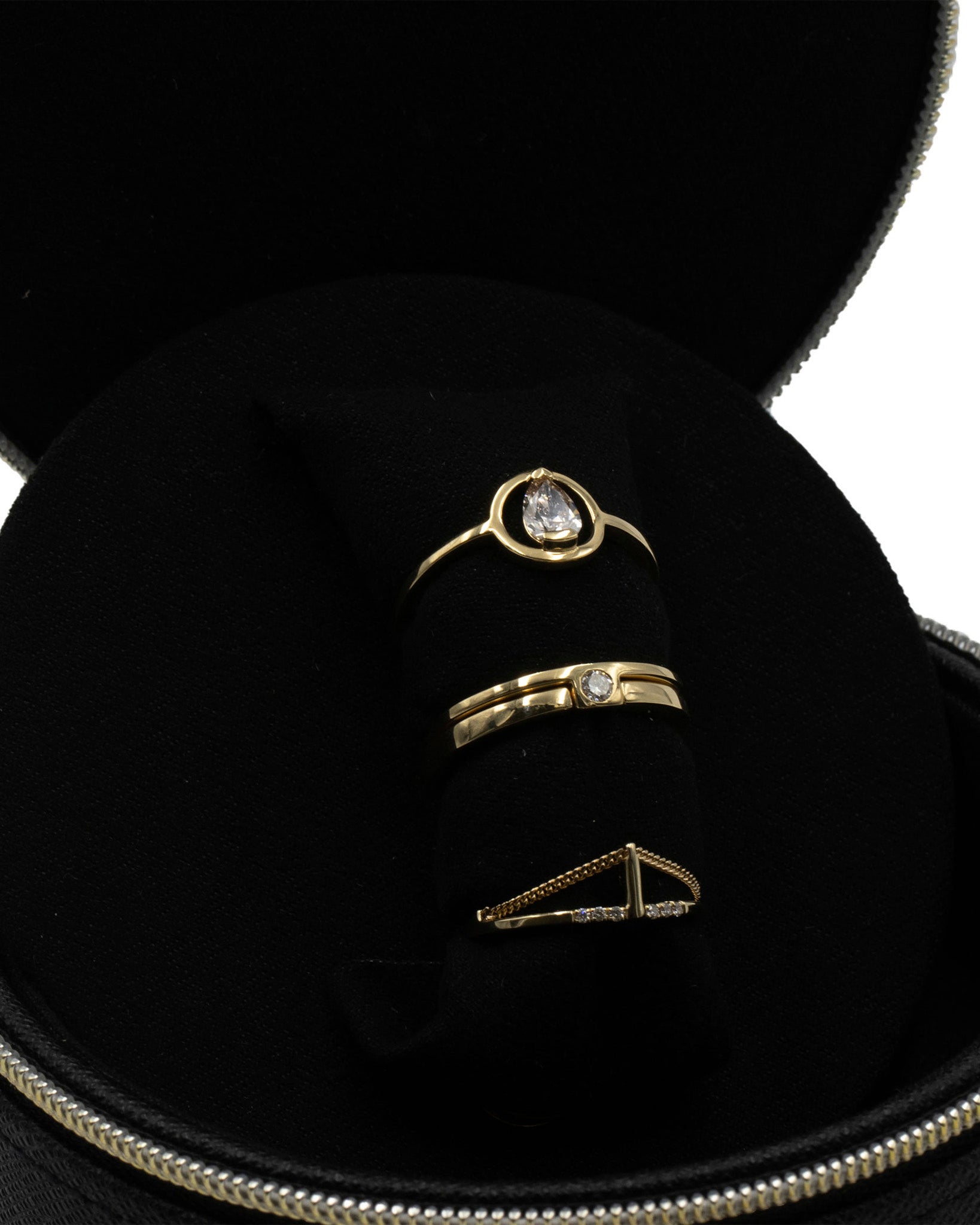 Elegant view of the Bliss Lau Jewelry Case featuring a stunning ring set, showcasing a black faux leather design with a gold zipper and multiple rings elegantly displayed inside.