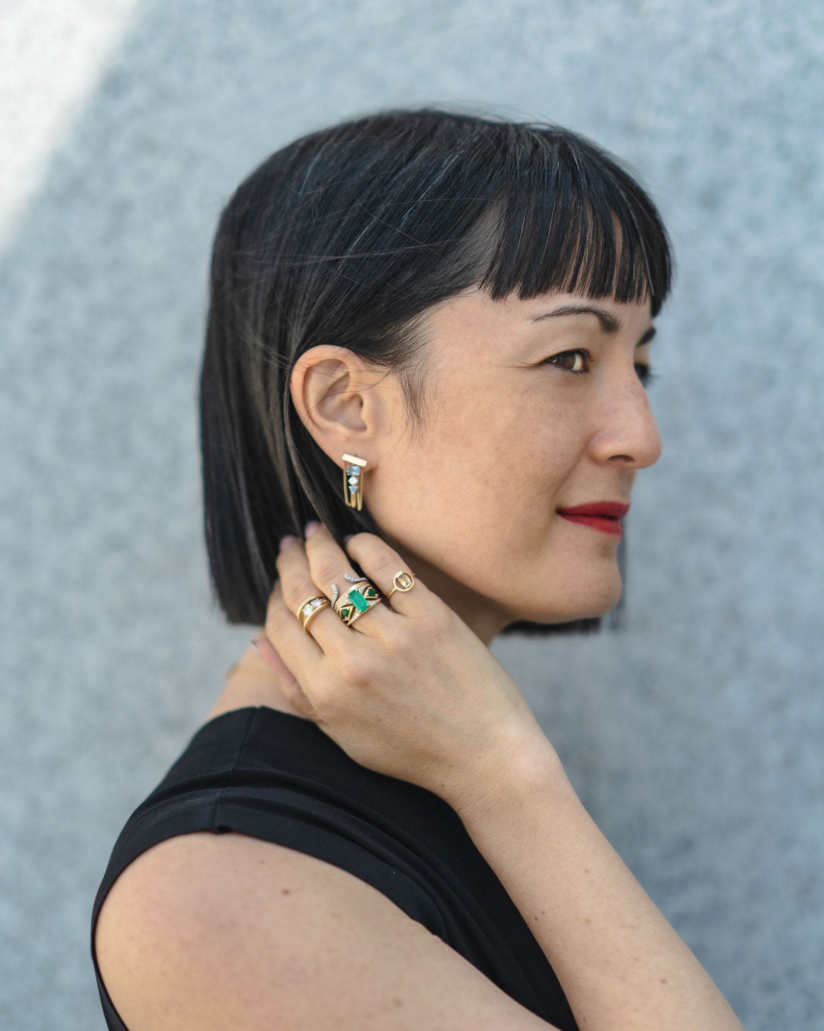 Profile image of a woman wearing the Mirage + Reflection Ring Set Emerald, radiating sophistication while showcasing the rings' luxurious appeal against her stylish look.