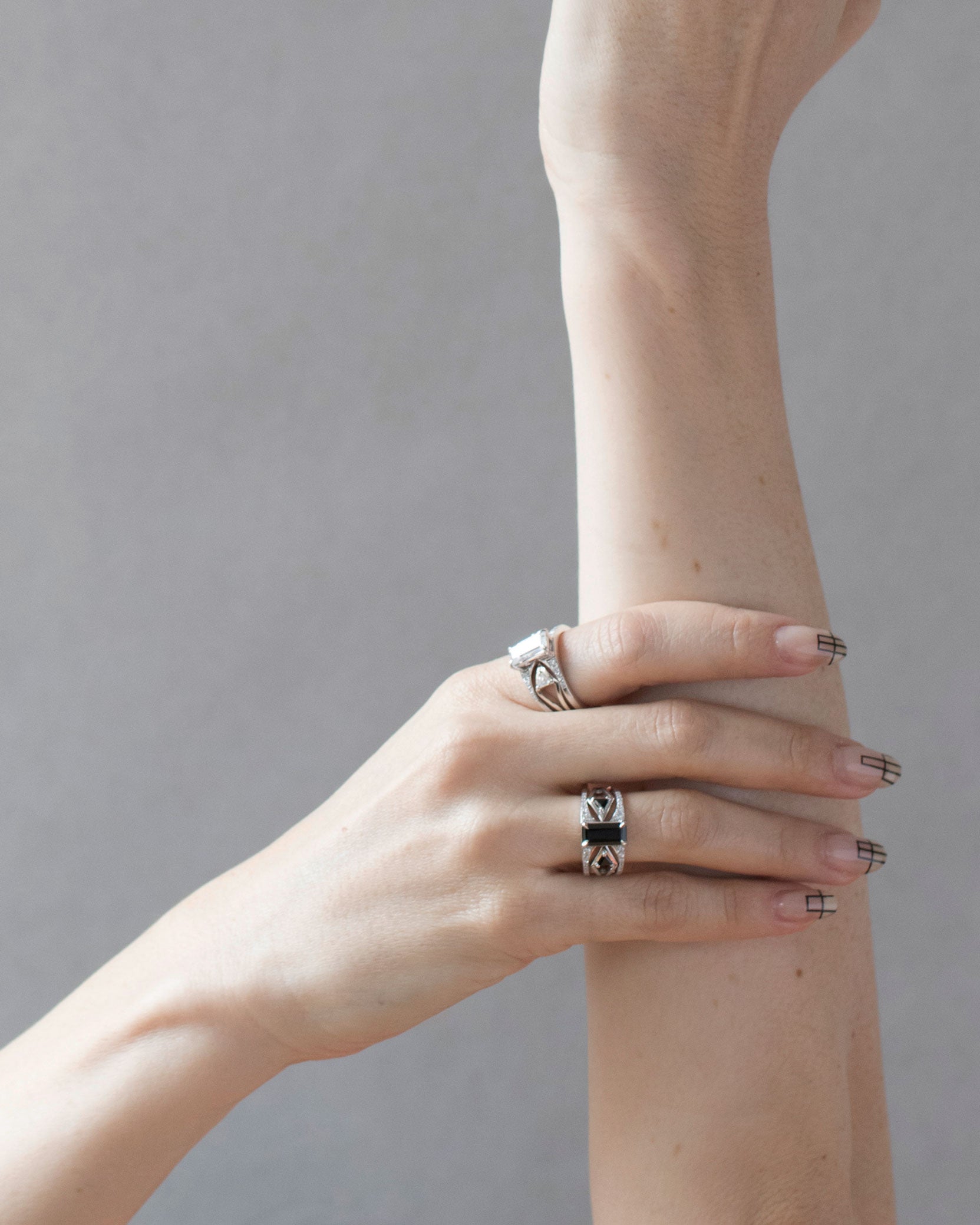 Model showcasing the exquisite Mirage + Reflection Ring Set with black spinel on fingers, highlighting the luxurious design in a chic, minimalist setting.