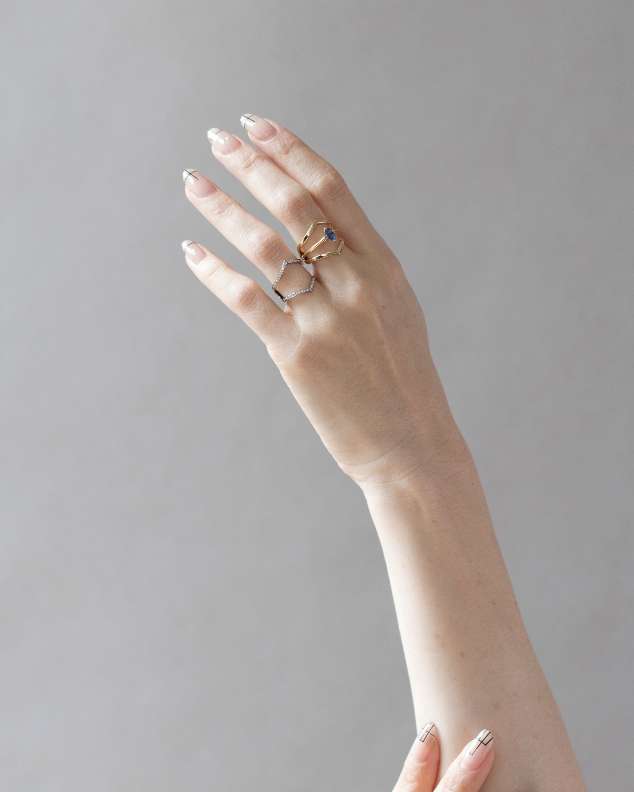 Minimalist Arc + Oblique Enclose Ring Set worn on a hand, highlighting its sophisticated and modern aesthetic in gold.