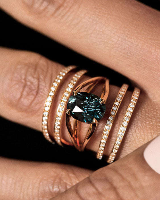 Close-up of interlocking wedding rings featuring a prominent red gem and elegant gold design, showcasing a modern and artistic touch perfect for couples.