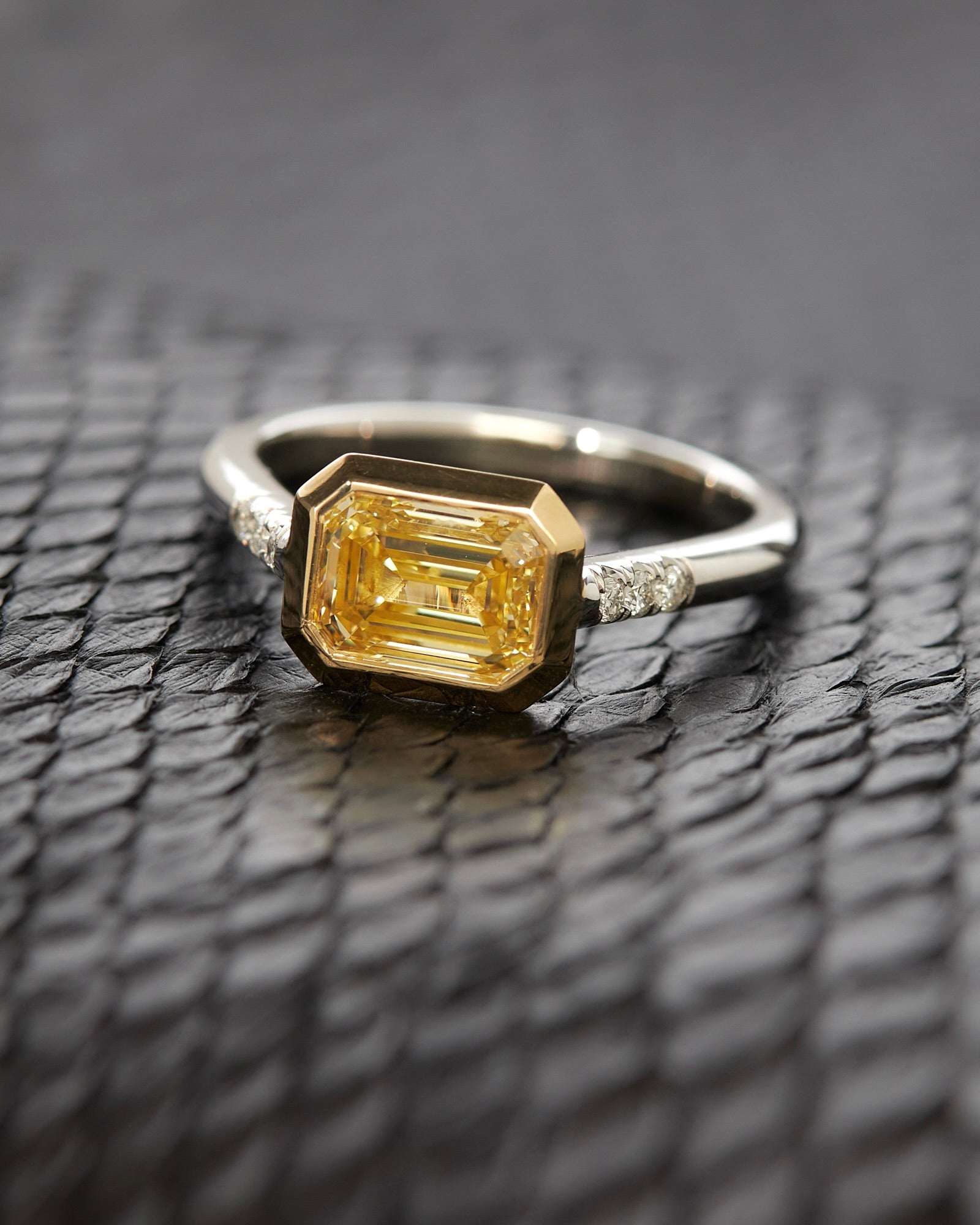 Luxury custom ring featuring an emerald cut yellow diamond set in a sleek band, designed by Bliss Lau.