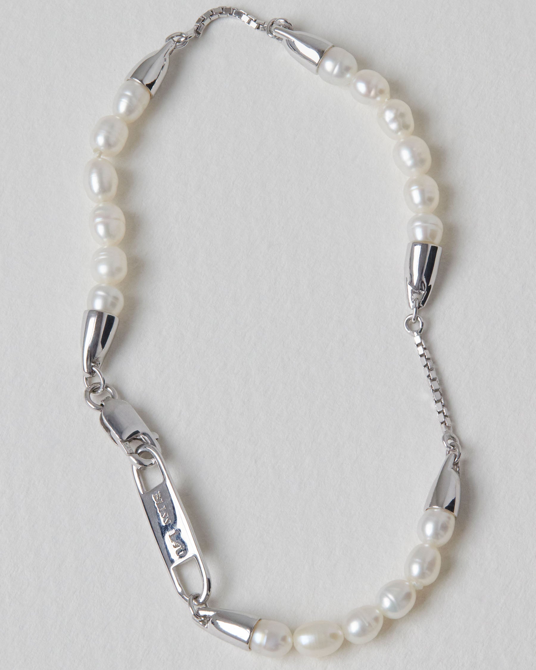 Pearl bracelet with silver clasp on a light gray background