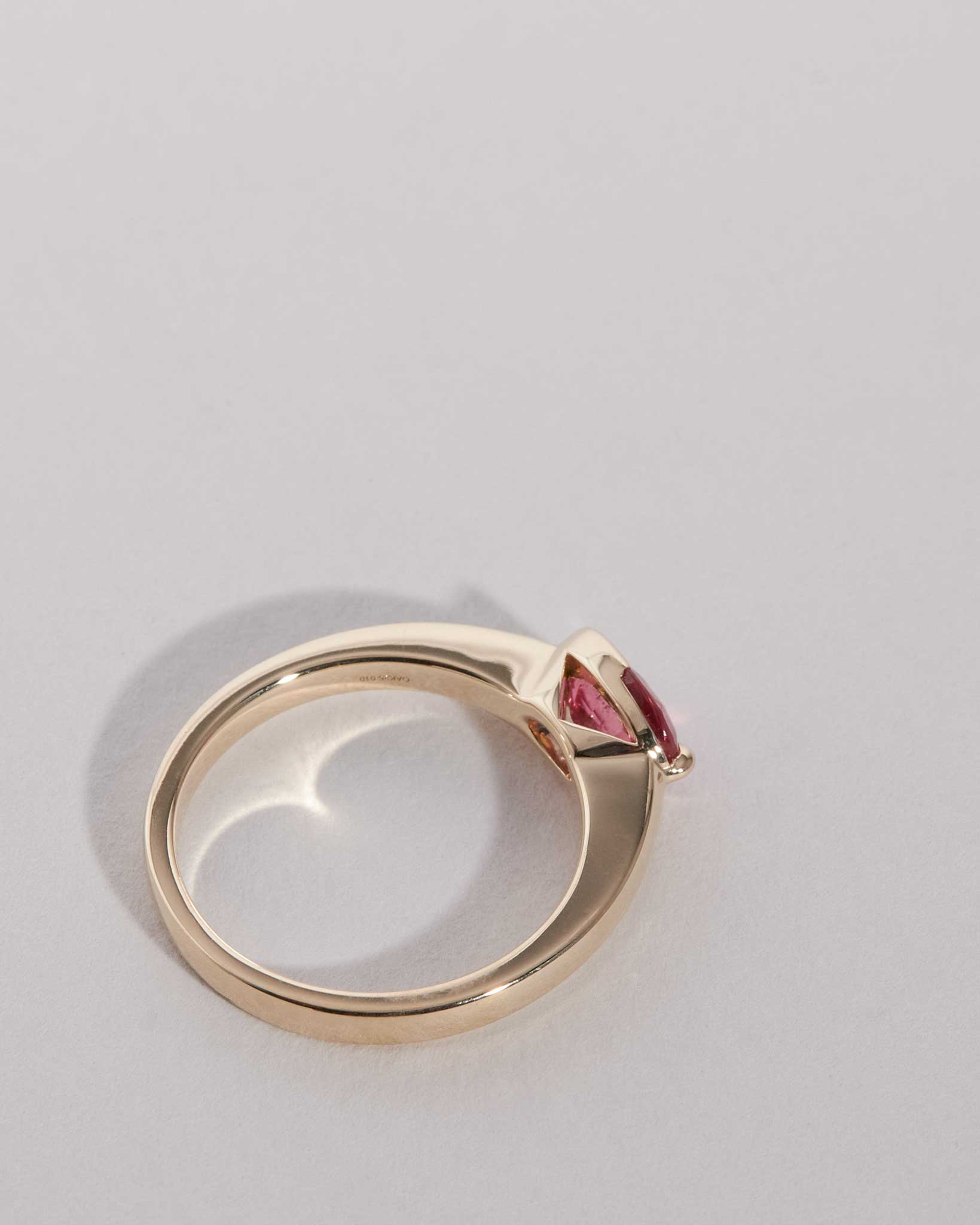 Gold ring with a red gemstone on a light gray background